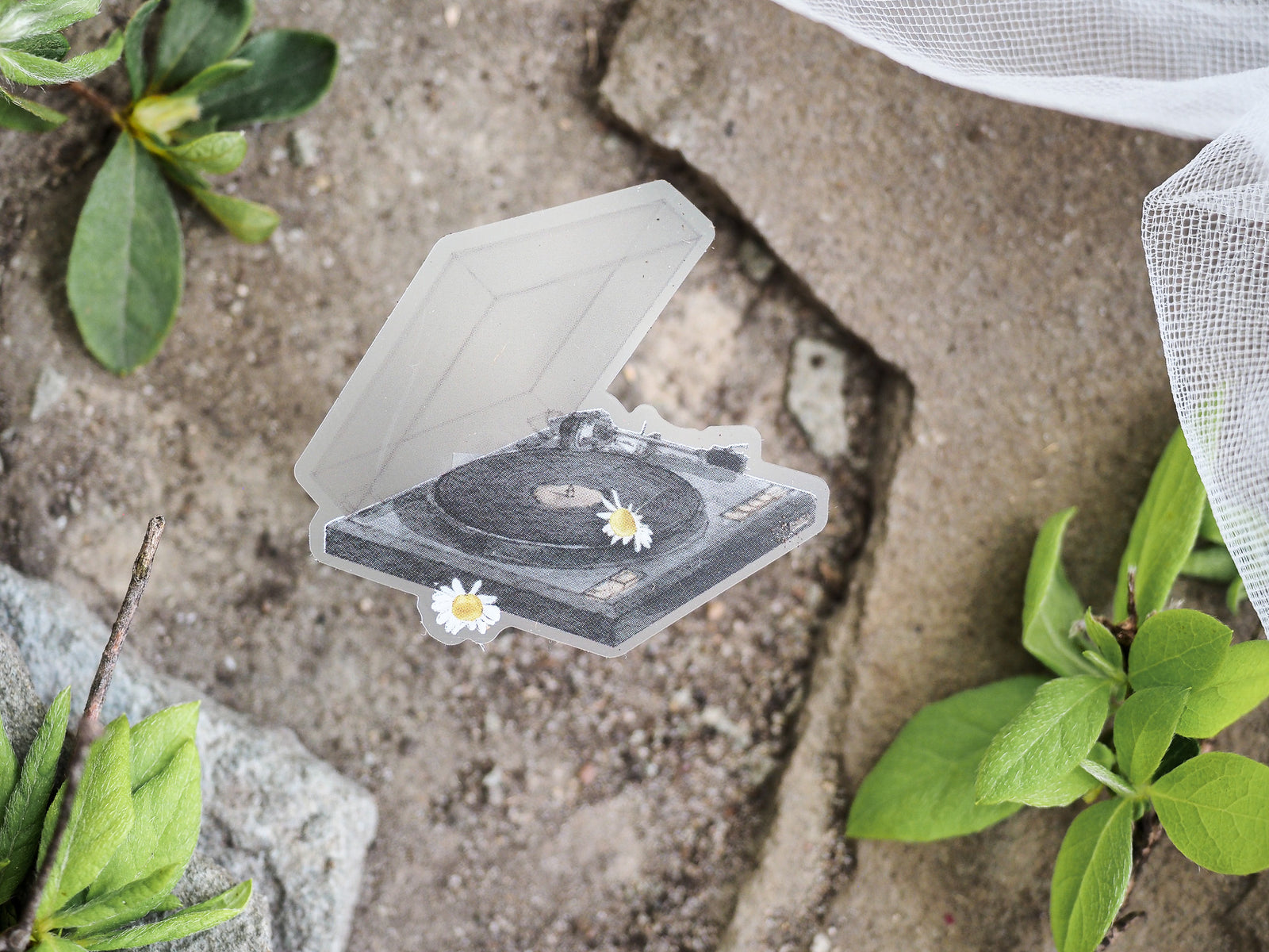 Vintage black and white die-cut sticker featuring an open box containing a turntable and vinyl records adorned with charming daisy illustrations.
