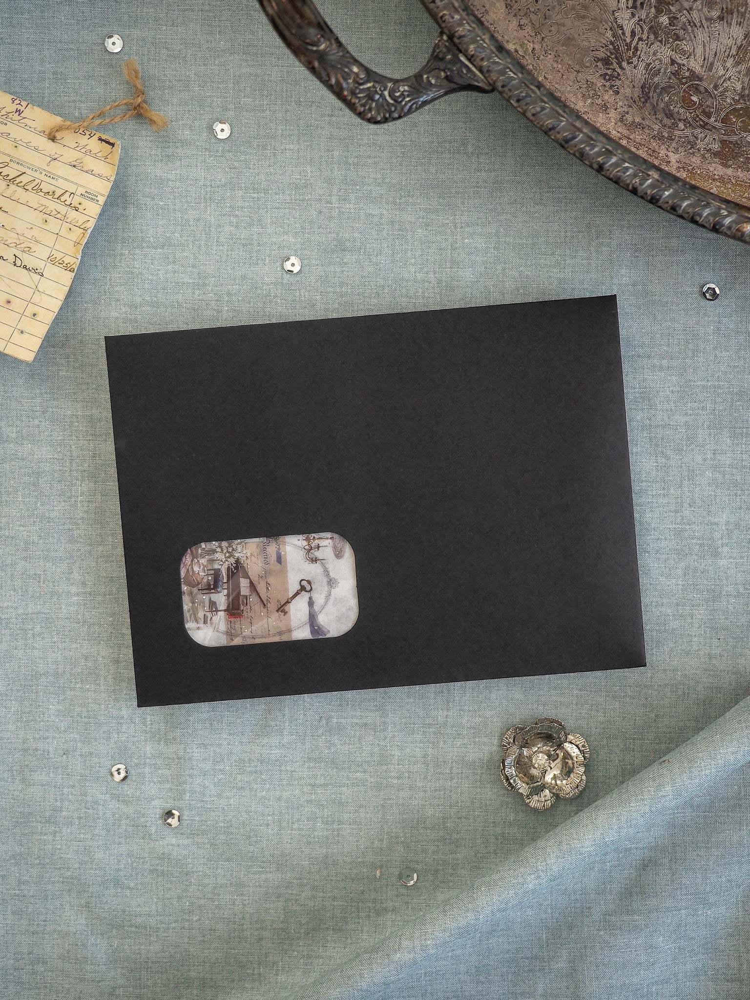 Black square card featuring a central, faded, vintage-style sticker illustration of an architectural sketch or building detail.