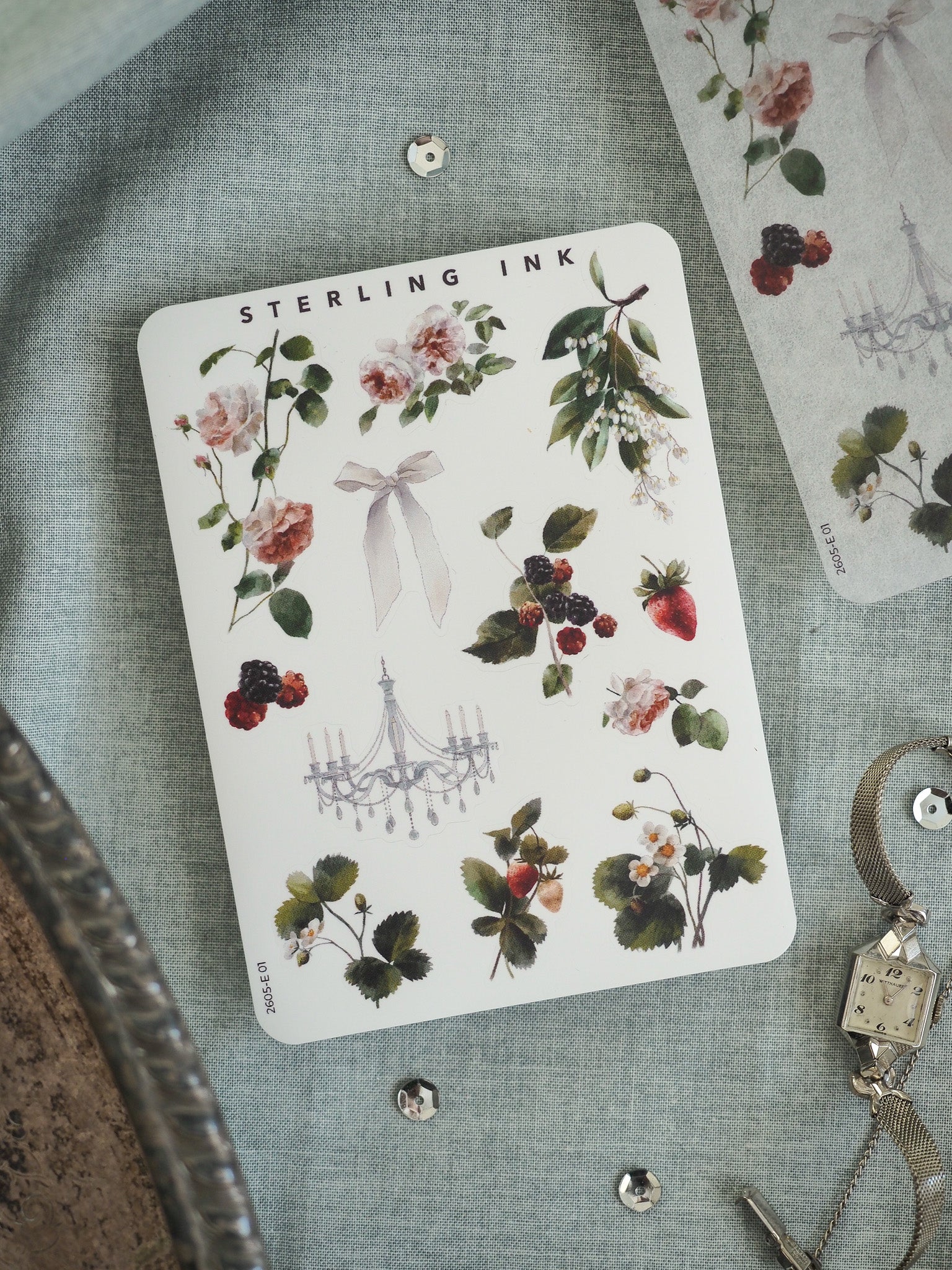 Watercolor botanical sticker featuring arrangements of pink roses, white flowers, green foliage, and deep red berries, accented by a delicate chandelier graphic.