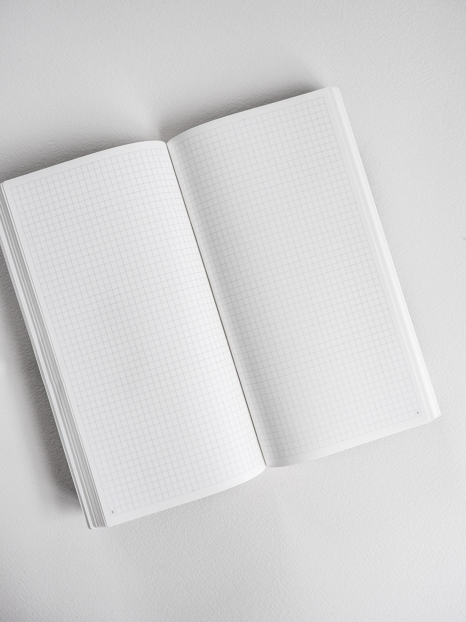 Open planner revealing two spreads of clean white graph paper, designed for comprehensive common planning, scheduling, and detailed note-taking.