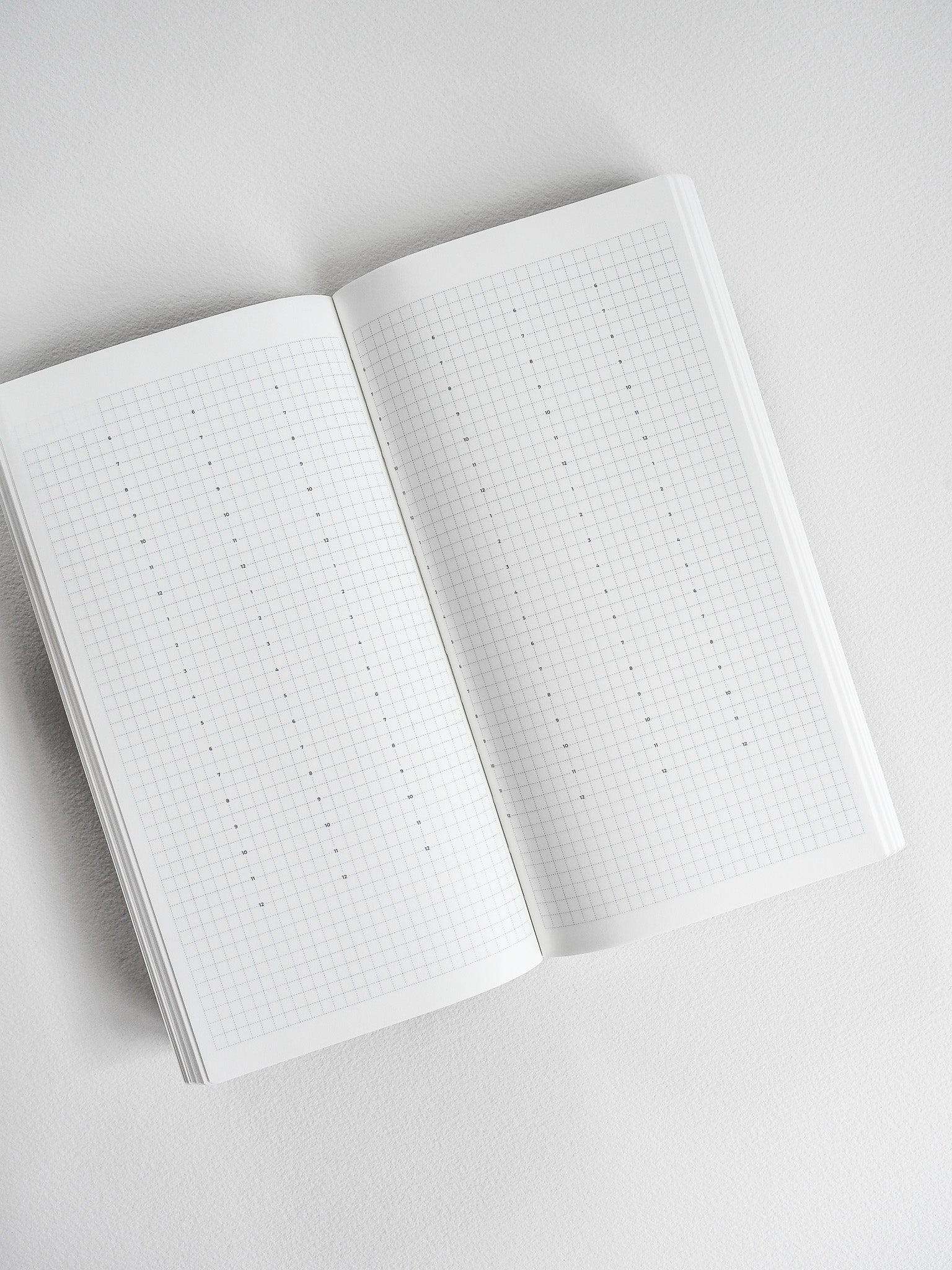 Open planner book showing two pages of crisp white, perfectly gridded graph paper, ideal for common planning, sketching, and note-taking.