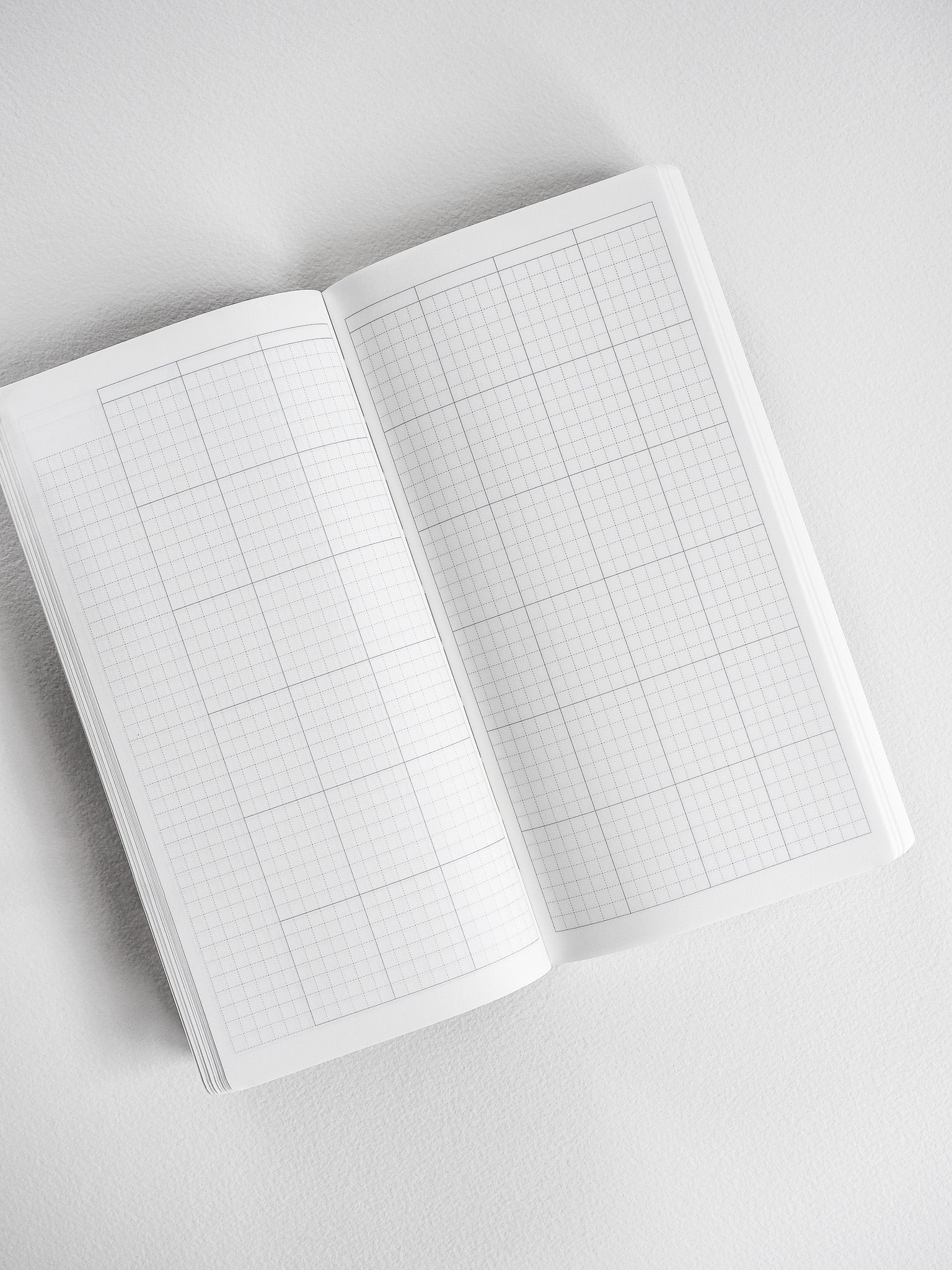 Open white planner featuring visible graph paper grids across both pages, perfect for undated, organized note-taking and scheduling.