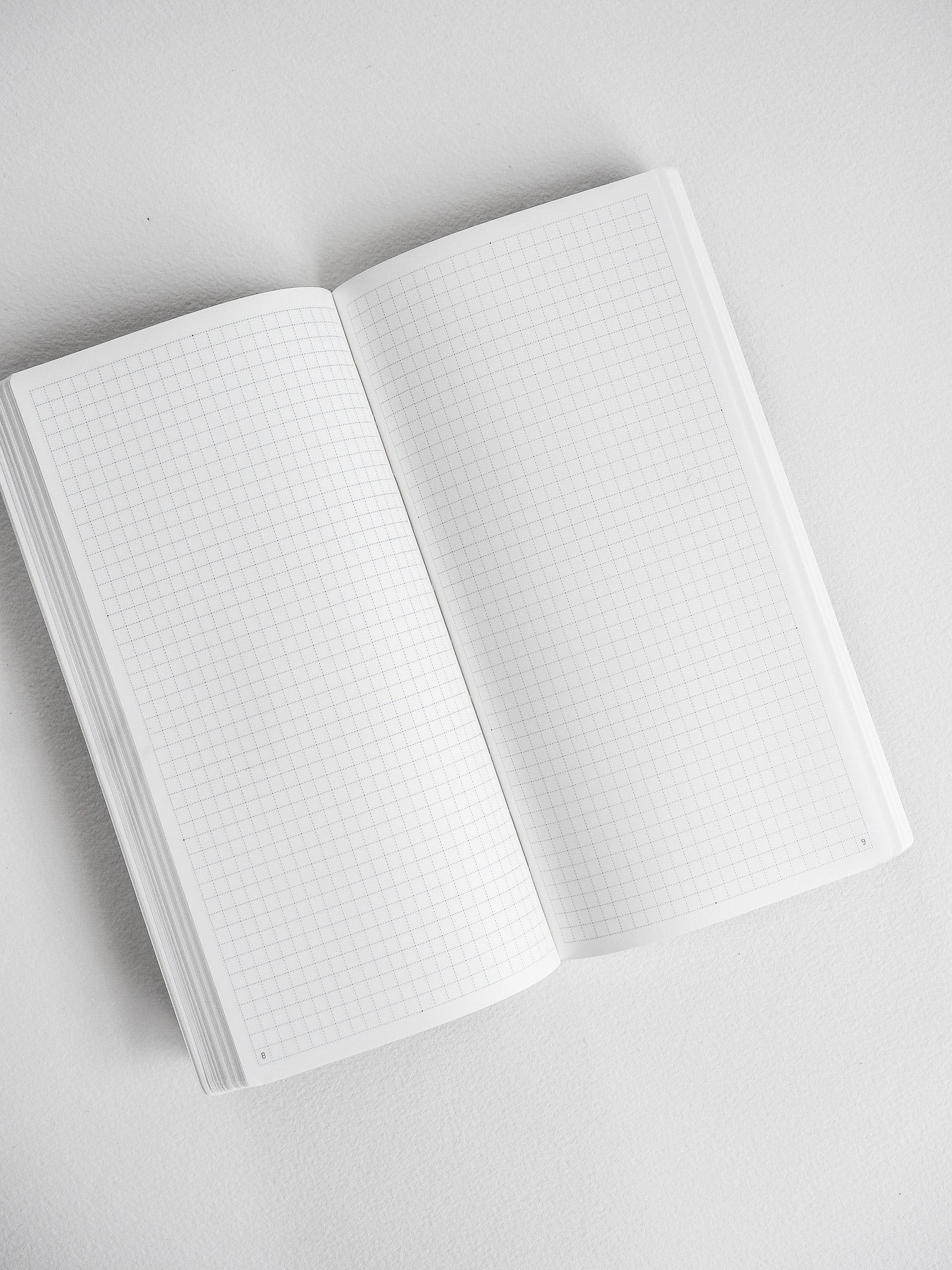 Open white undated planner displaying crisp graph paper grids across both pages for comprehensive yearly scheduling and detailed note-taking.