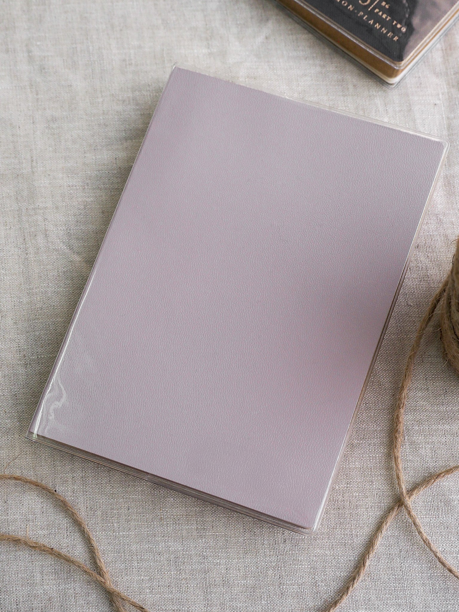 Minimalist, clear protective sleeve featuring a smooth, solid light mauve panel, ideal for adding a subtle pop of color to any planner or notebook.