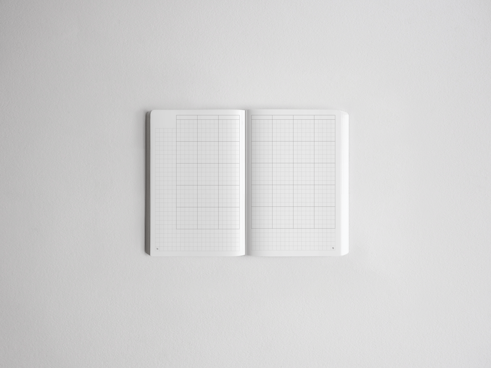 Open notebook featuring two pages of light gray graph paper grids, perfect for drawing, charting, or structured note-taking.