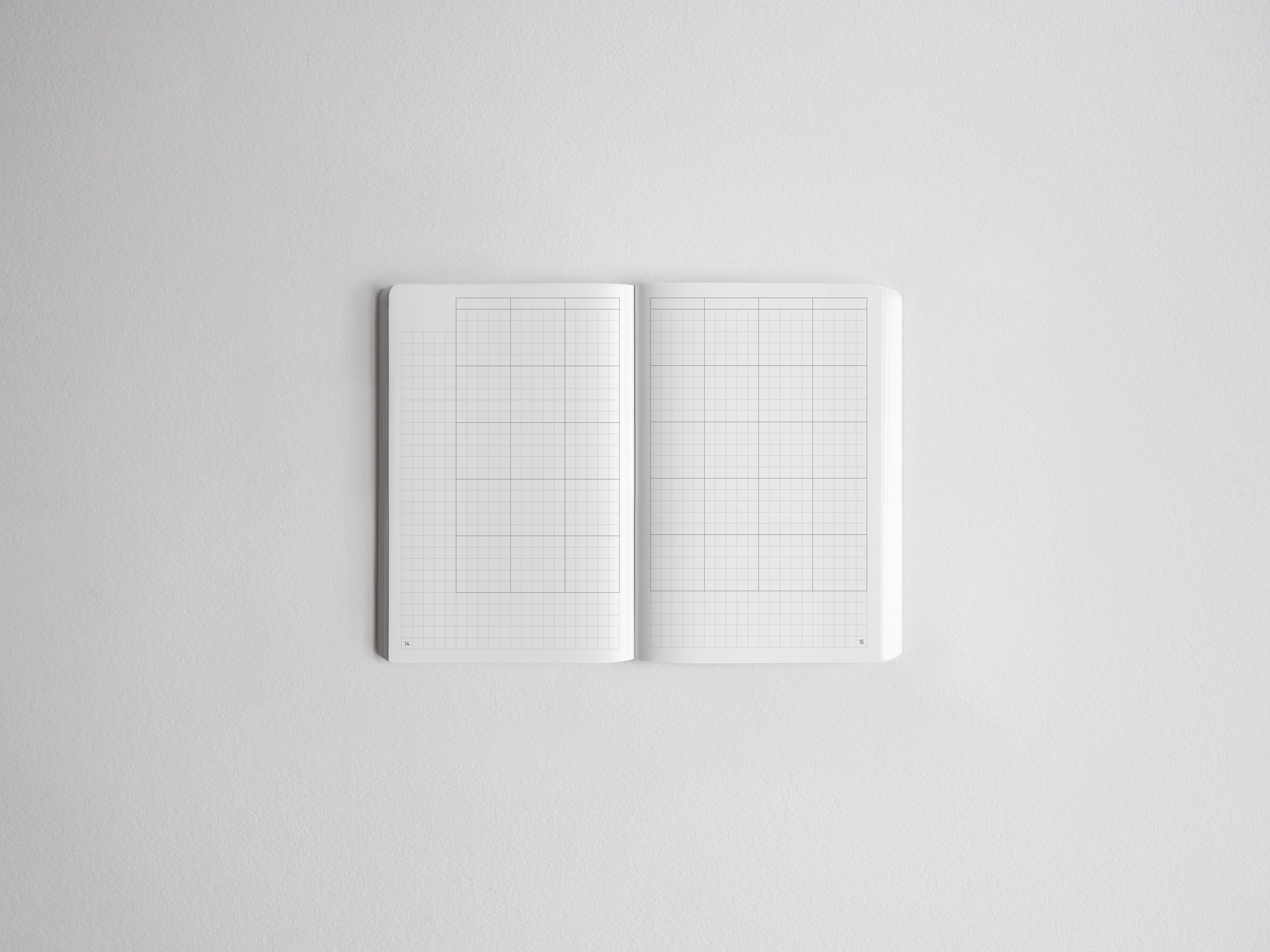 Open notebook featuring two pages of light gray graph paper grids, perfect for drawing, charting, or structured note-taking.