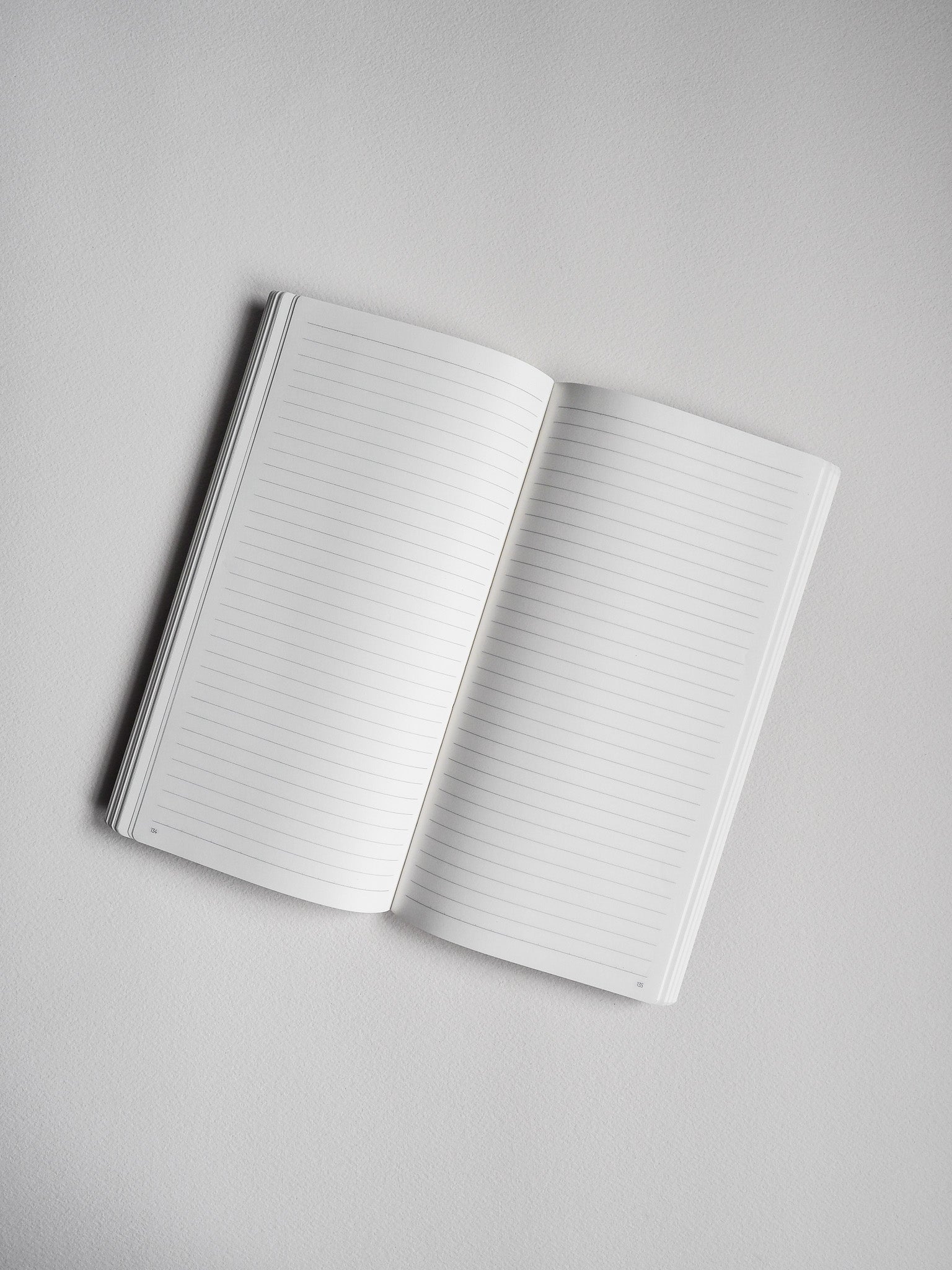 Open notebook displaying crisp white, ruled pages with visible sequential page numbers, ideal for notes and journaling.