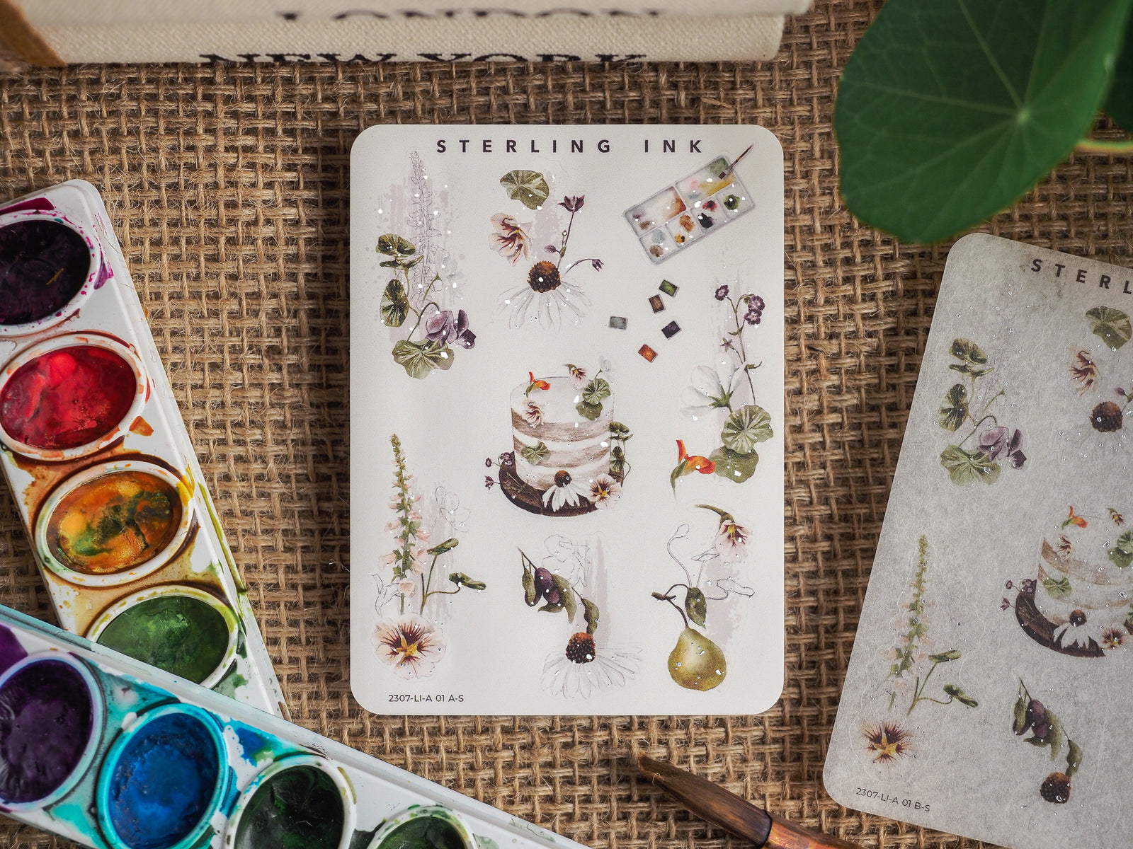Botanical icon sticker sheet featuring detailed watercolor illustrations of flowers, plants, and baked goods with delicate silver foil accents.