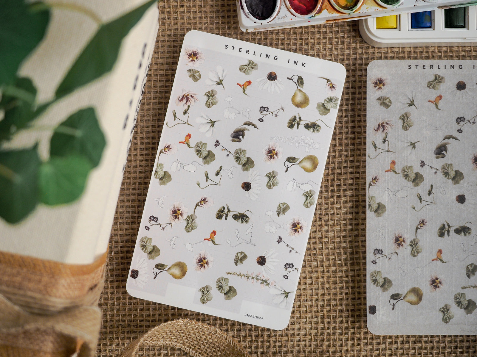 A delicate sheet of botanical stickers featuring a natural pattern of small, detailed illustrations of white and pink flowers, leaves, and scattered berries.