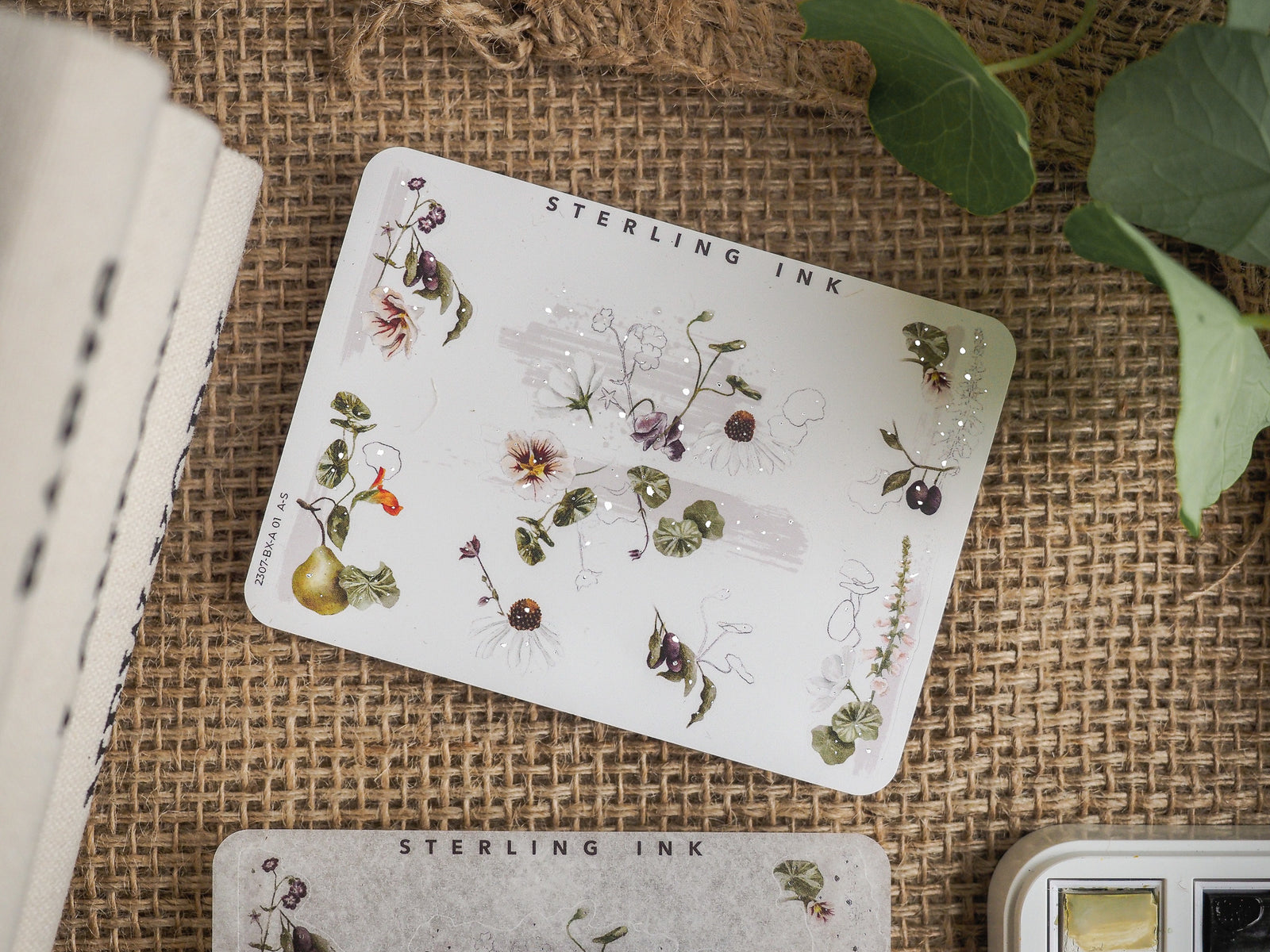 Delicate botanical sticker set featuring detailed watercolor illustrations of purple flowers, green leaves, and small berries accented with subtle silver foil.