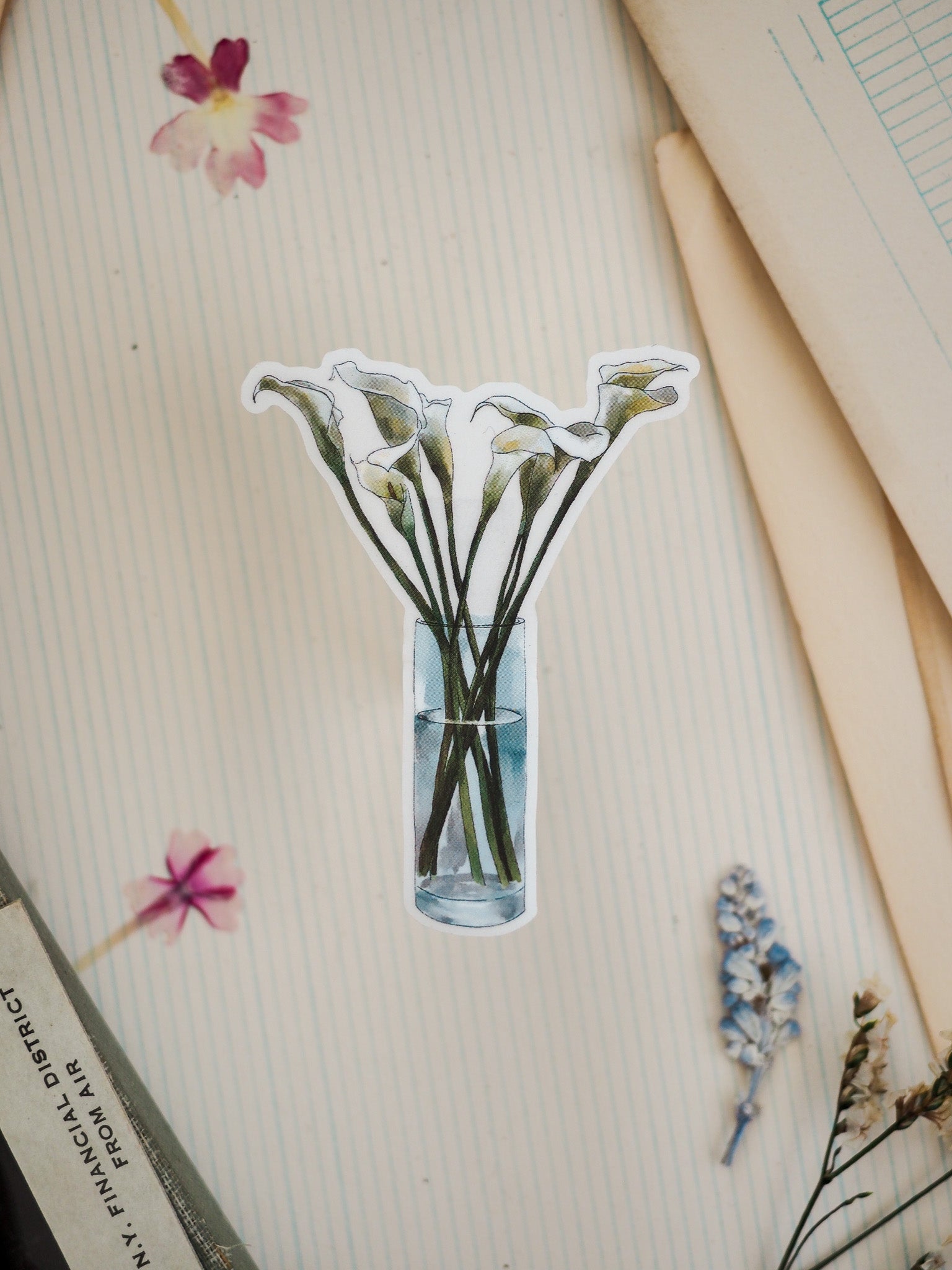 A sticker featuring a watercolor illustration of white calla lilies displayed in a clear glass vase.