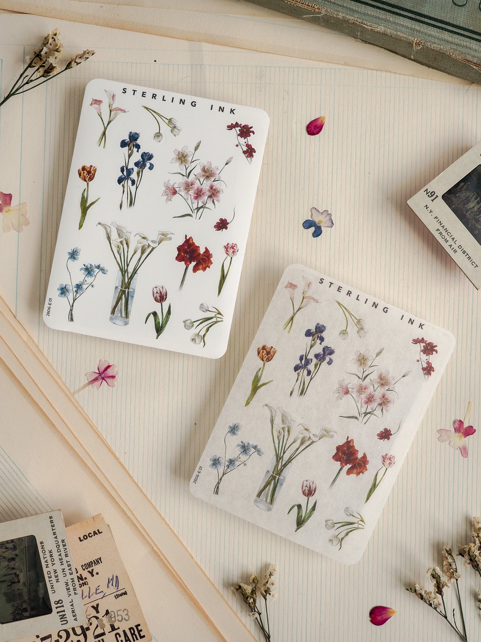 Pair of "Sterling Ink" notepads featuring soft watercolor botanical prints of diverse spring wildflowers and lush greenery.