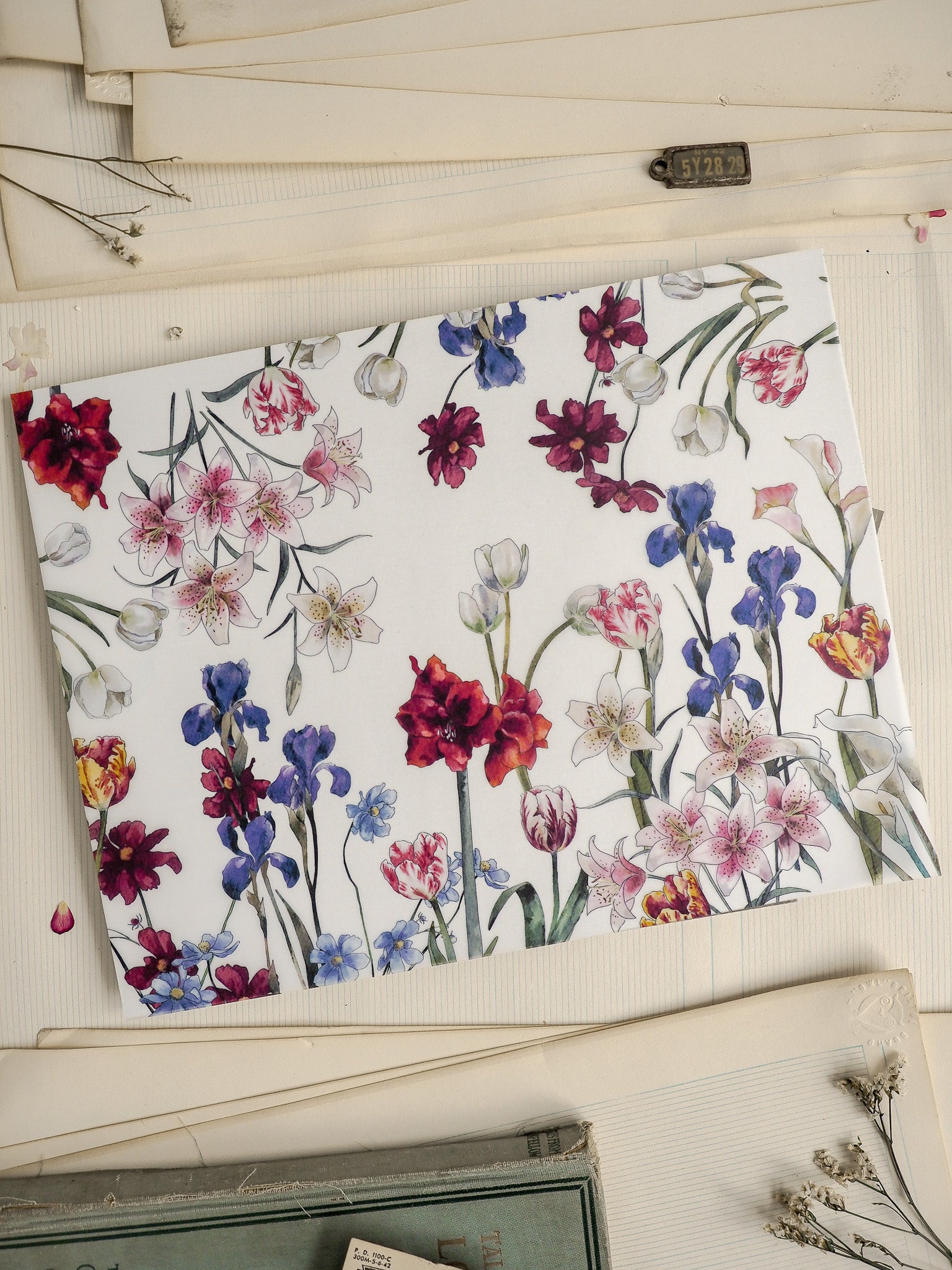 Vibrant floral pattern featuring mixed blooms like lilies, roses, and lilac clusters in rich jewel tones of deep red, blue, and purple on a crisp white background.