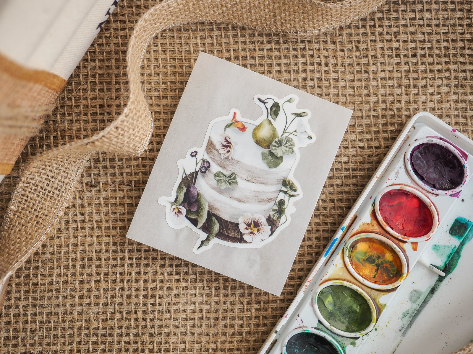 Die-cut vinyl sticker sheet featuring a decorative white layered cake adorned with grapes, berries, and foliage, ideal for baking enthusiasts.