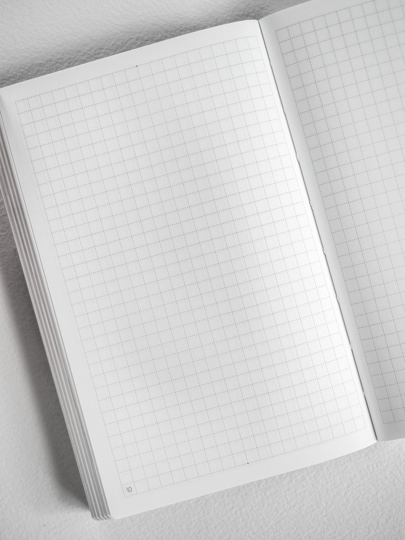 Open pocket monthly booklet displaying crisp, light-colored gridded graph paper pages, perfect for structured planning and journaling.