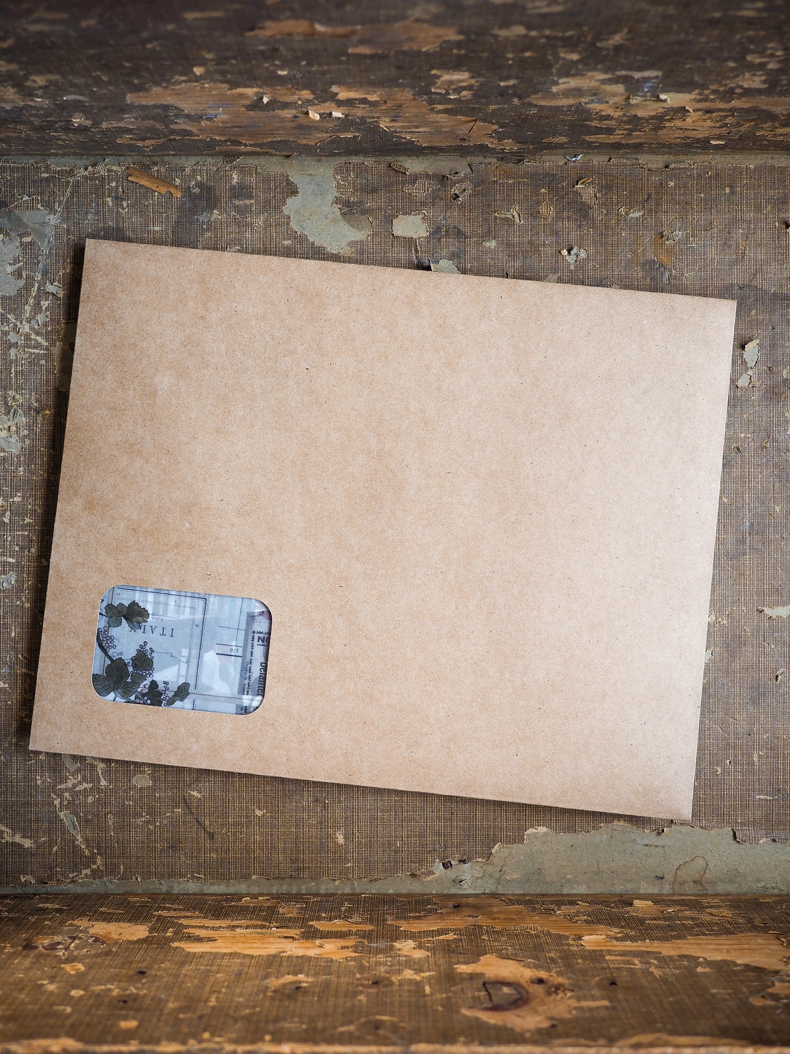 Light brown kraft cardstock featuring a small, rectangular sticker with distressed, layered print designs suitable for scrapbooking or journaling.