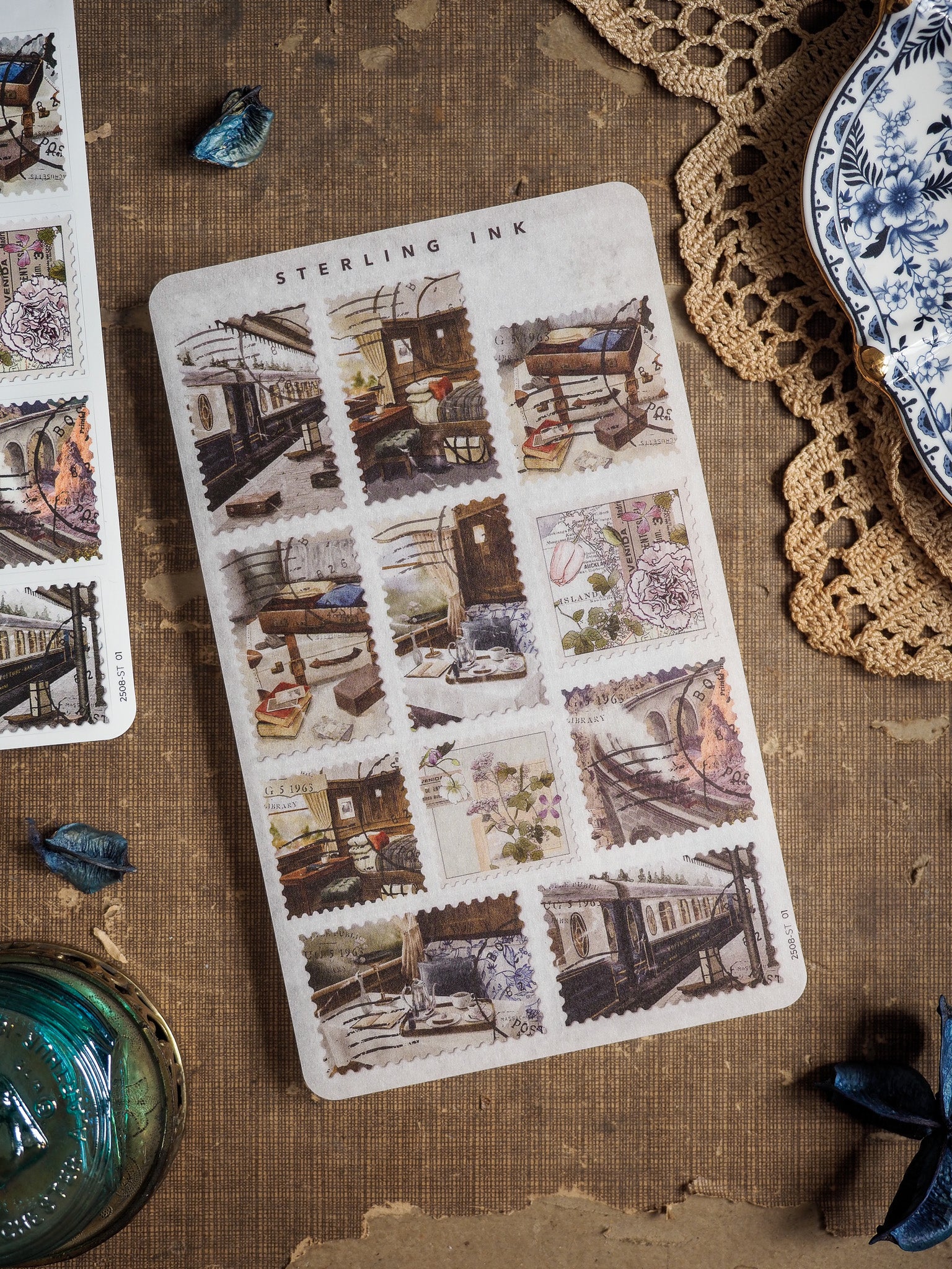 Vintage "Sterling Ink" stamp stickers for August 2025, featuring a grid of distressed, antique illustrations depicting detailed scenes of old city buildings and storefronts.
