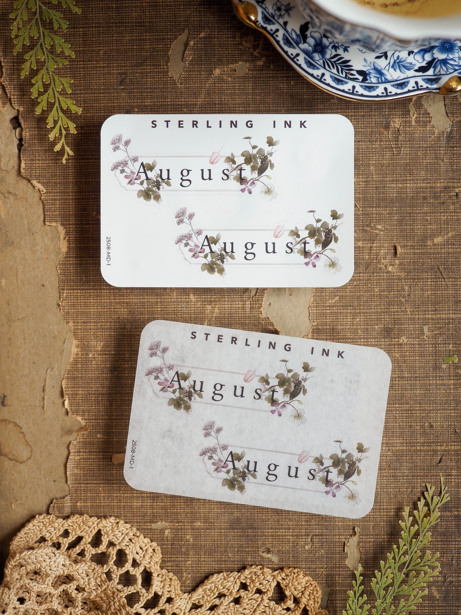 Three coordinating August month stickers featuring elegant botanical watercolor illustrations of purple blooms and green foliage on a soft cream background.