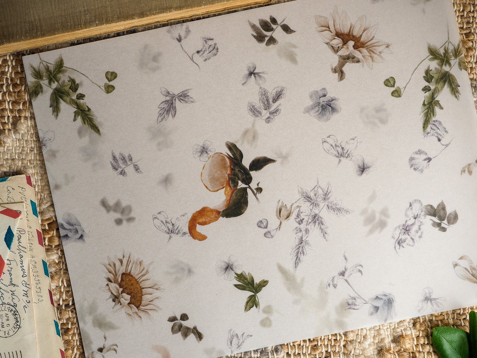 Delicate botanical pattern featuring scattered autumnal flora, leaves, and muted-toned wildflowers printed on a light cream background.