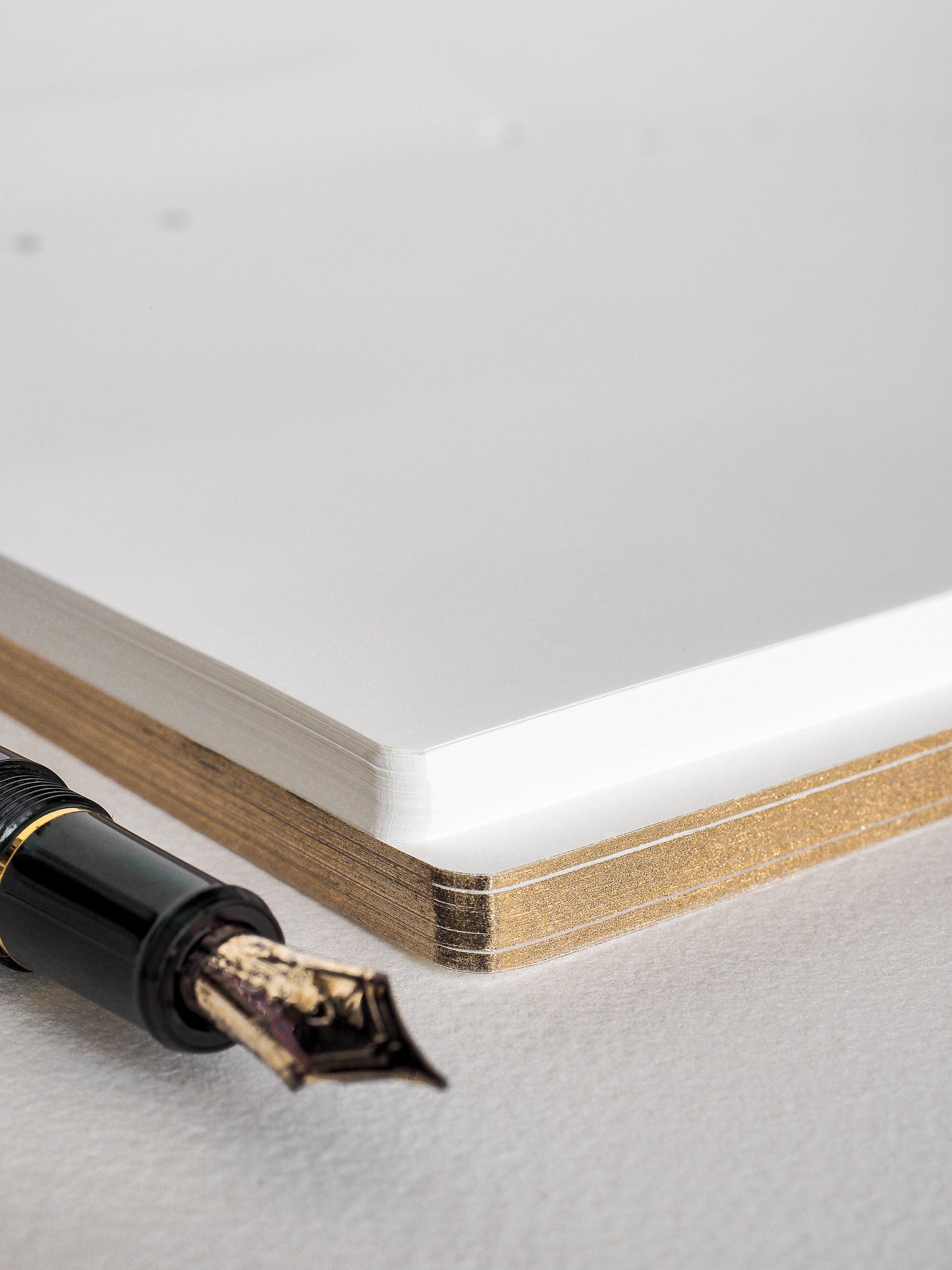 A pristine stack of plain white loose-leaf paper, showing crisp, golden-hued edges, ready for writing or journaling inserts.