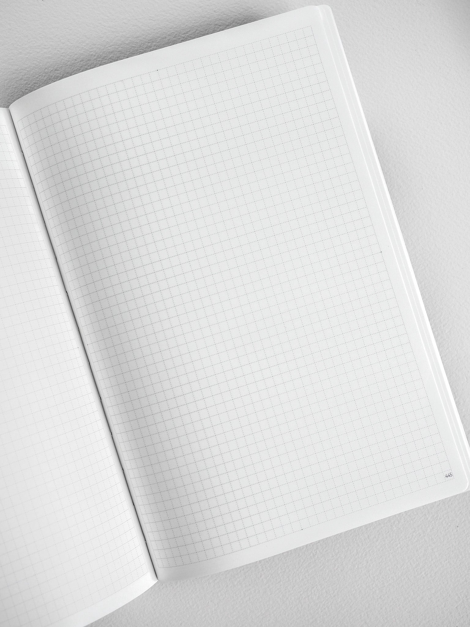 Open A5 graph notebook displaying structured light gray grid paper, perfect for detailed journaling, planning, or technical note-taking.