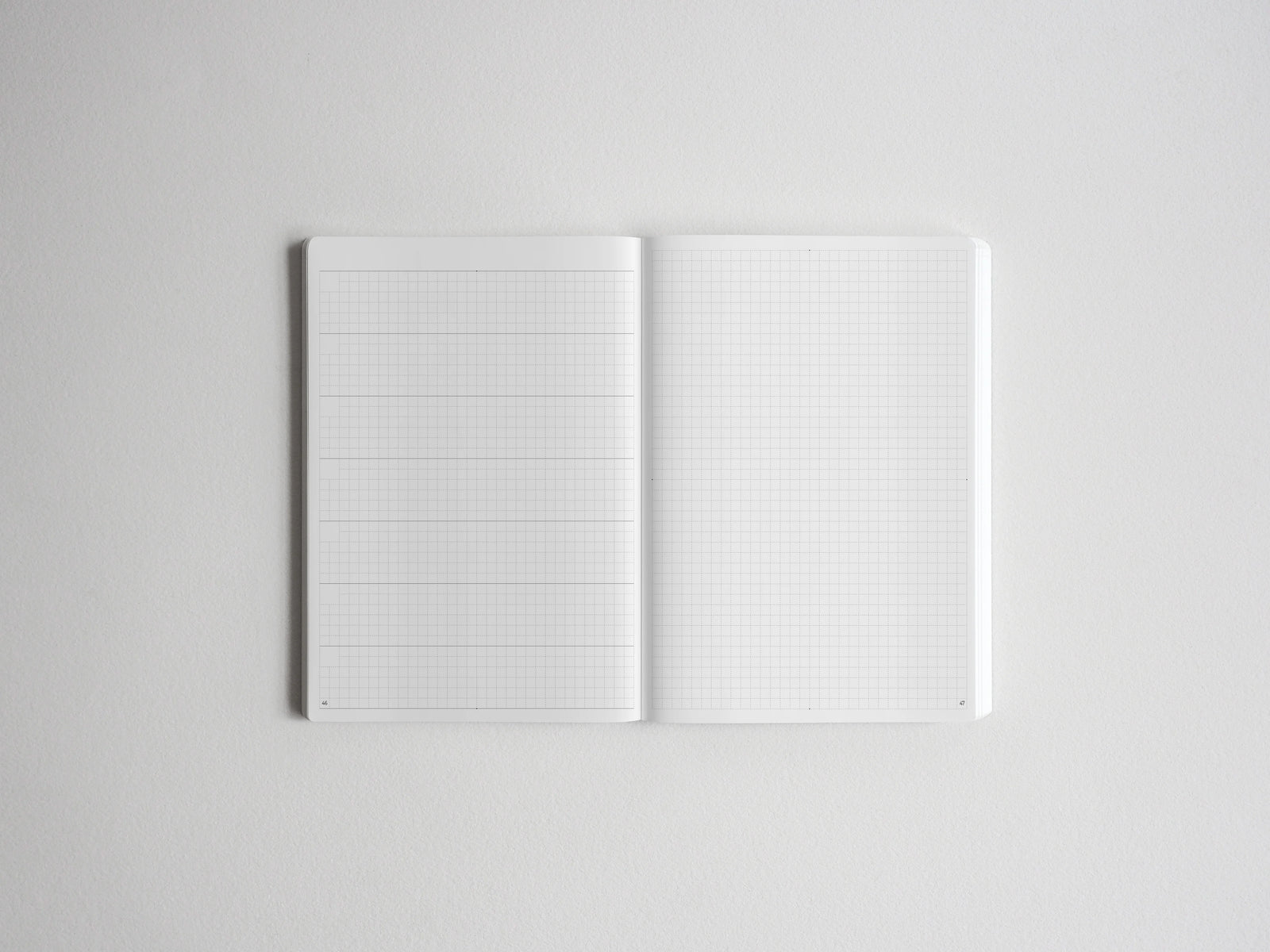 Open notebook displaying two pristine pages covered in a precise, light-colored graph paper grid, ideal for sketching, drafting, or structured note-taking.