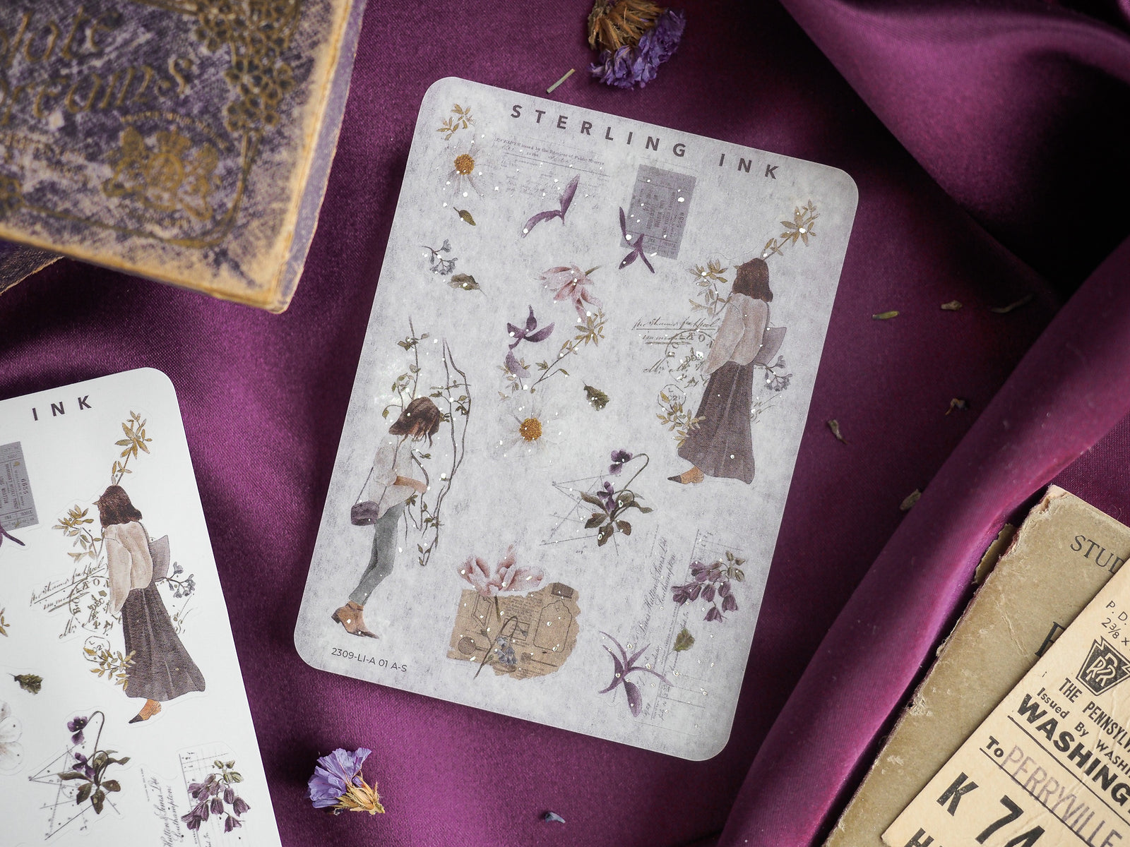 Vintage sticker sheet featuring botanical illustrations, delicate figures, and accents of sparkling silver foil on a muted gray background.