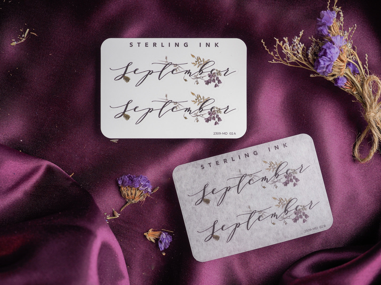 Elegant cream month planner stickers featuring "September" in flowing script typography and adorned with delicate printed clusters of sepia-toned botanicals.