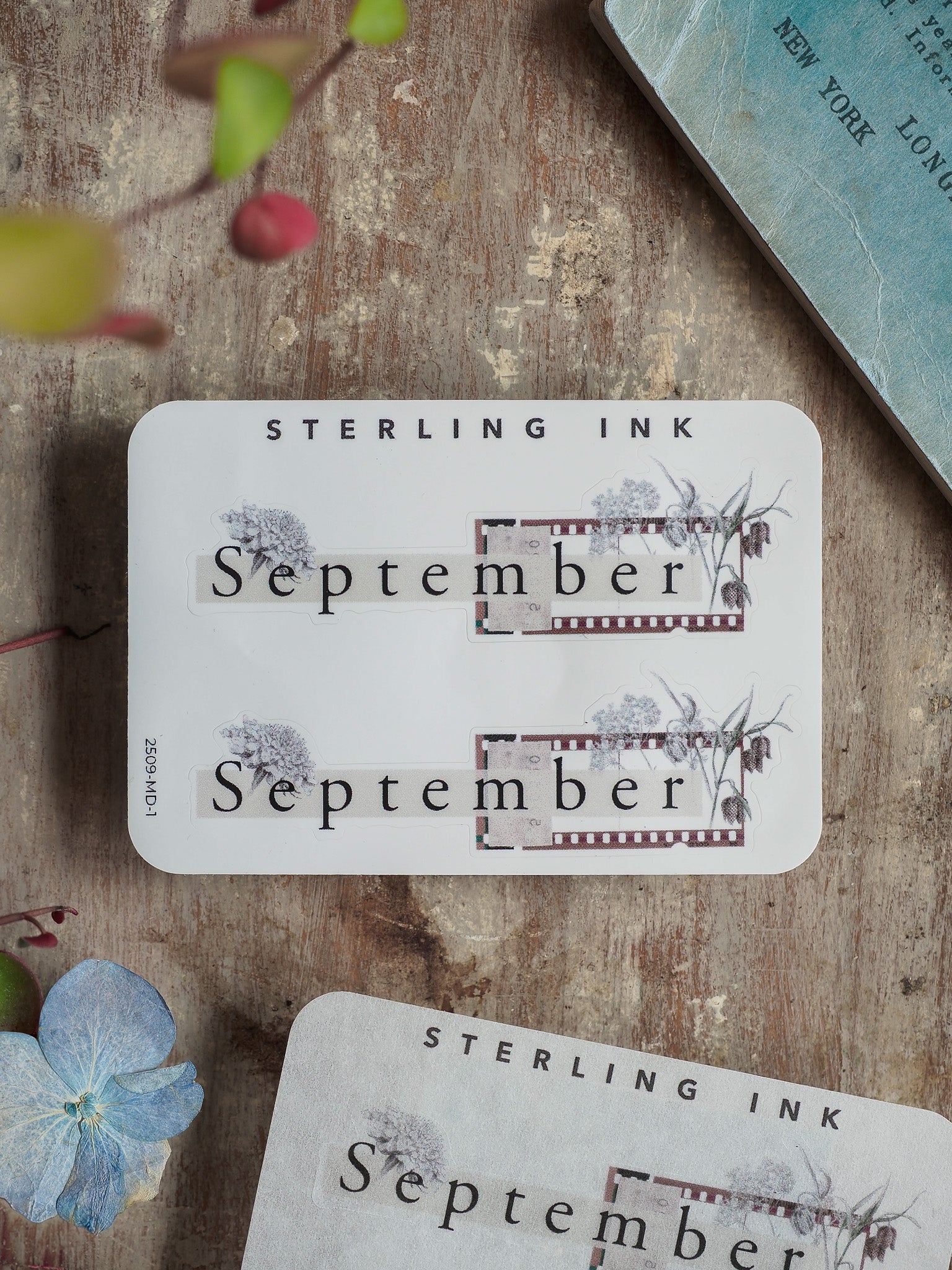 Watercolor-accented monthly "September" sticker by Sterling Ink, featuring delicate gray and purple florals and a clean, elegant design for journaling or scrapbooking.