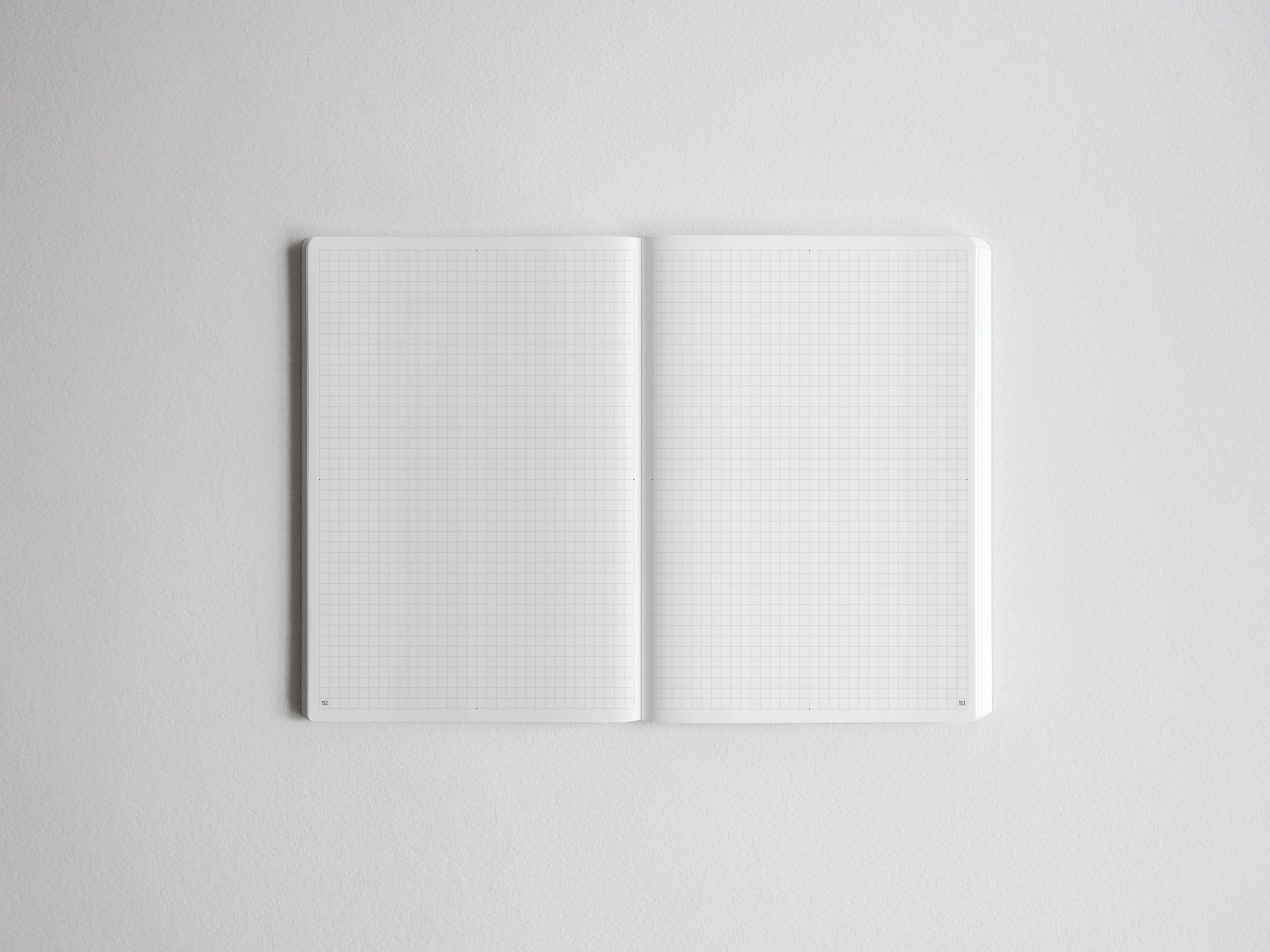 Open spiral notebook showcasing two blank pages of light gray graph paper, perfect for creative sketching, journaling, or academic tracking.