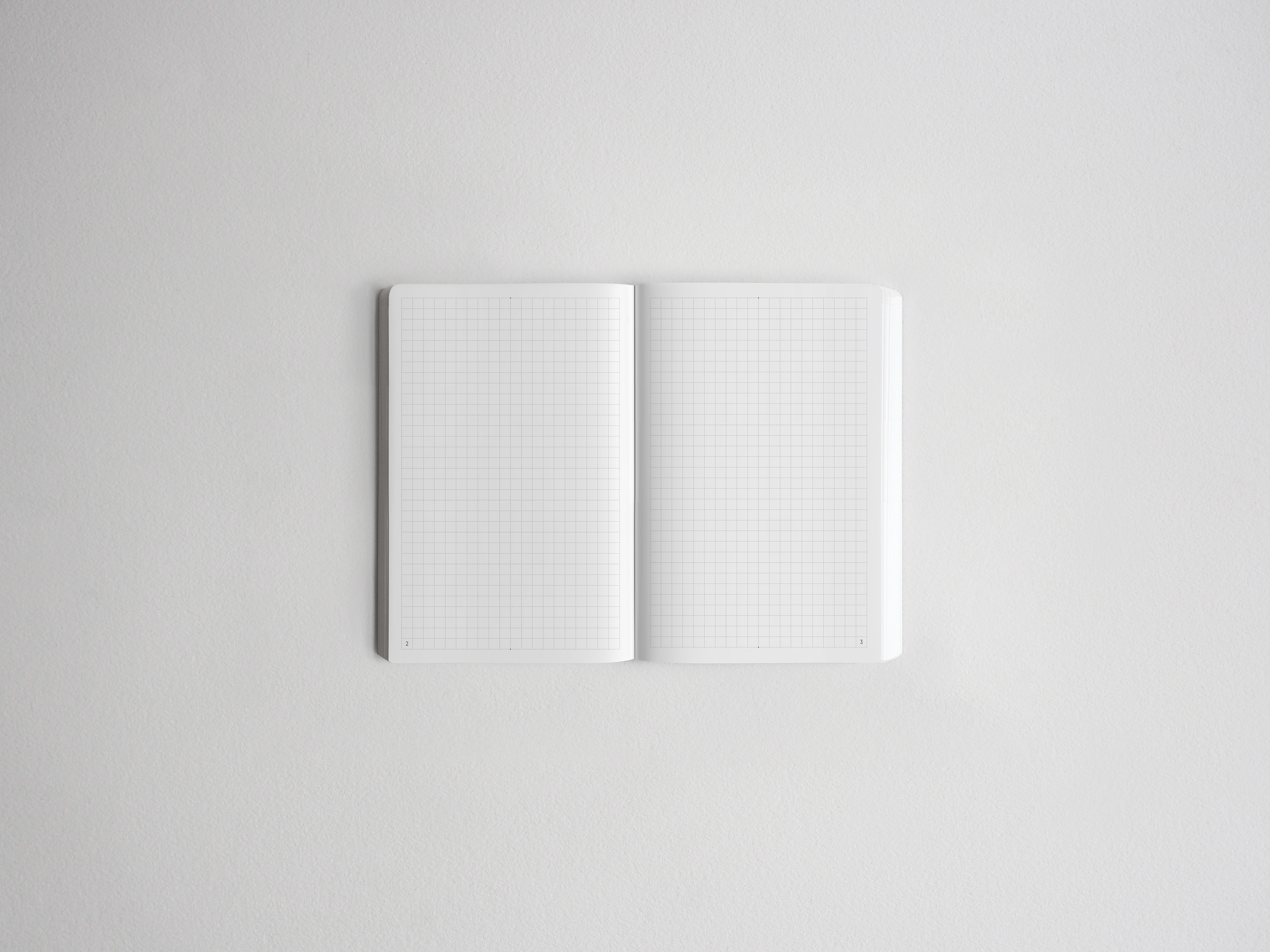 Open notebook displaying white graph paper grids on both pages, ideal for planning, drawing, or journaling.