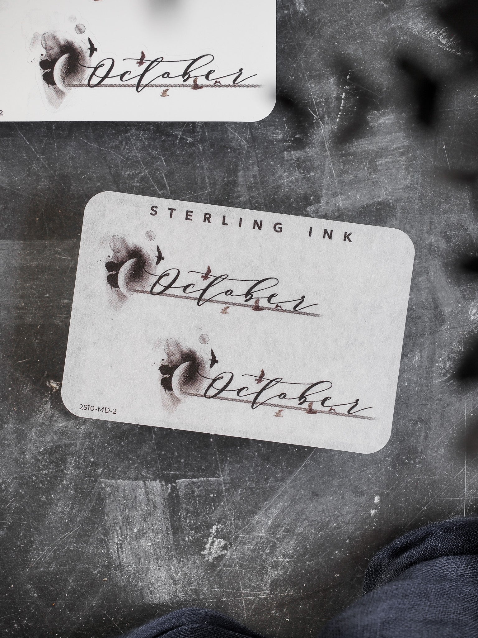 Decorative 'October' month sticker featuring rich sepia-toned lettering and small whimsical accents, ideal for enhancing scrapbooks and personalized planners.