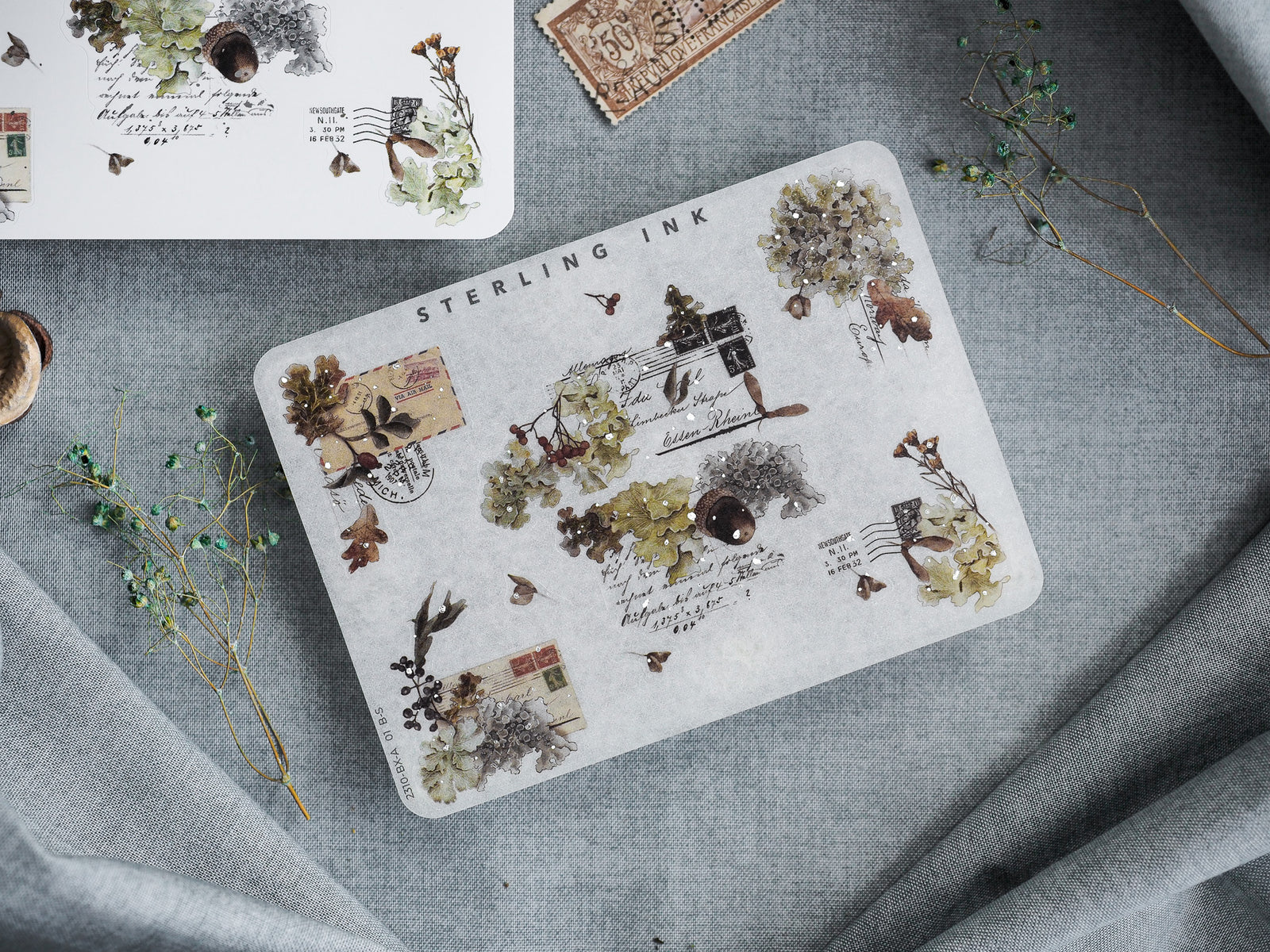 Botanical-themed sticker collage featuring distressed vintage stamps, archival ink splatters, and delicate pressed flora for scrapbooking.