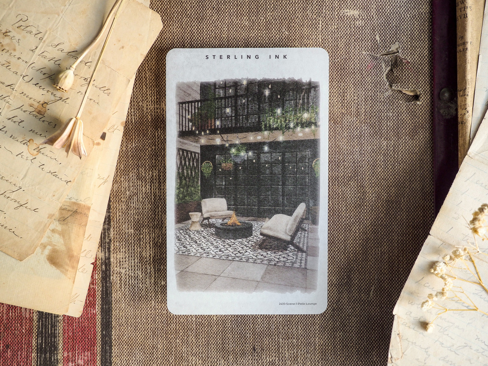 Black and white scene illustration of an inviting outdoor patio lounge, featuring comfortable seating, greenery, and a fire pit for a cozy autumnal vibe.