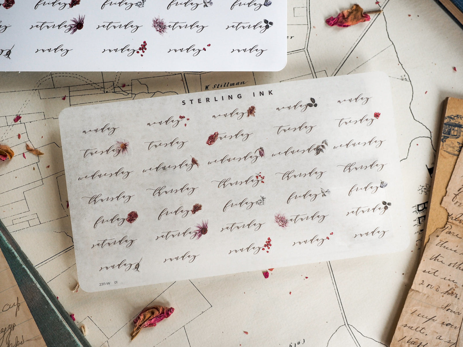 White sticker sheet featuring a calendar design with red ink printing the days of the week for November 2023, including stars and decorative floral accents.