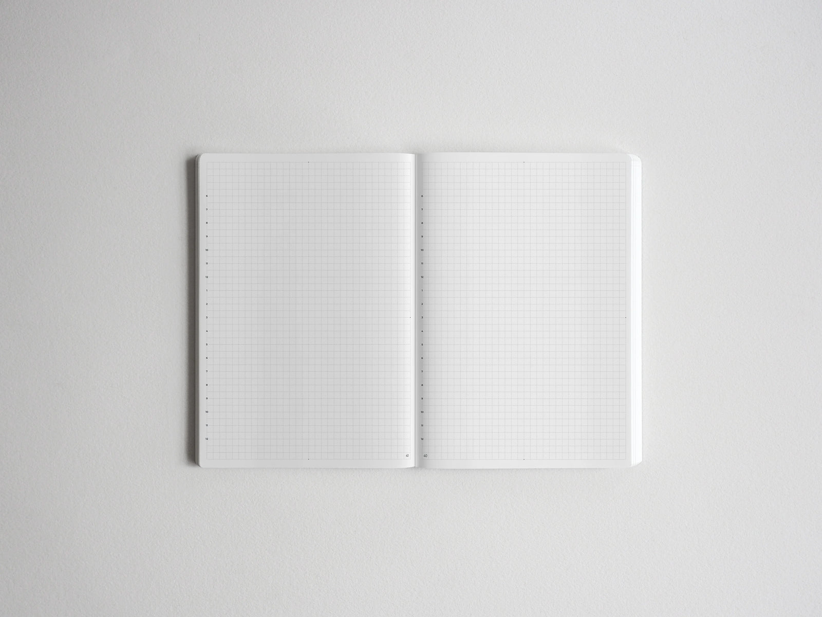 Open spiral notebook displaying two clean pages of white graph paper, featuring visible grid lines for drawing, studying, or professional note-taking.