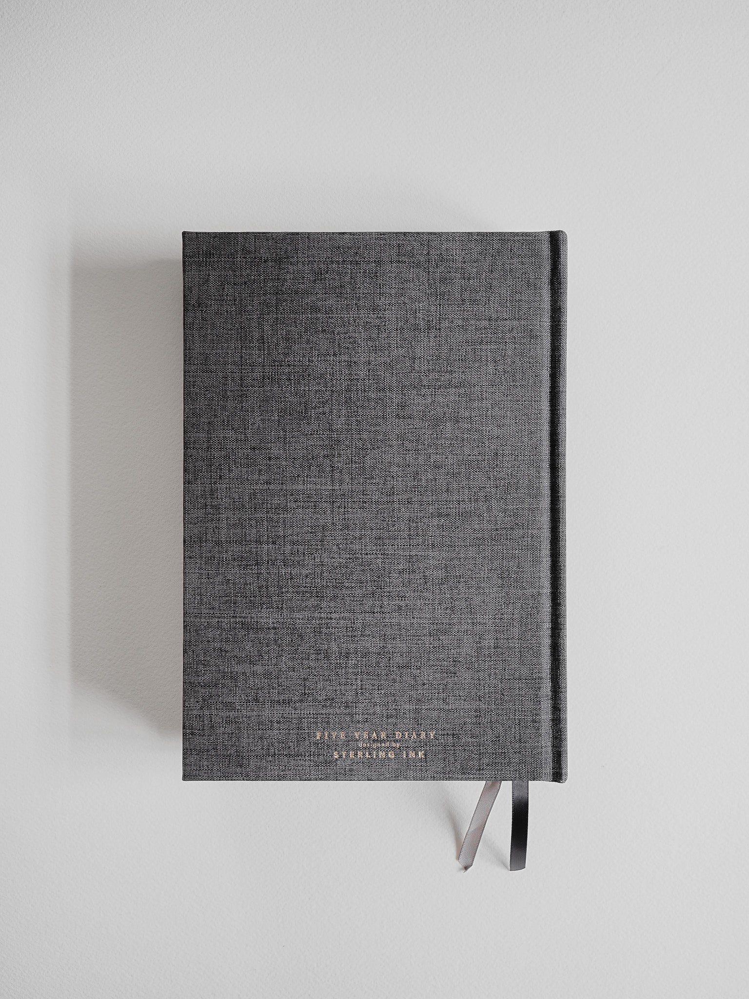 Textured, solid gray A5 hardcover diary featuring subtle brand lettering and secured with two minimalist dark metal clasps.