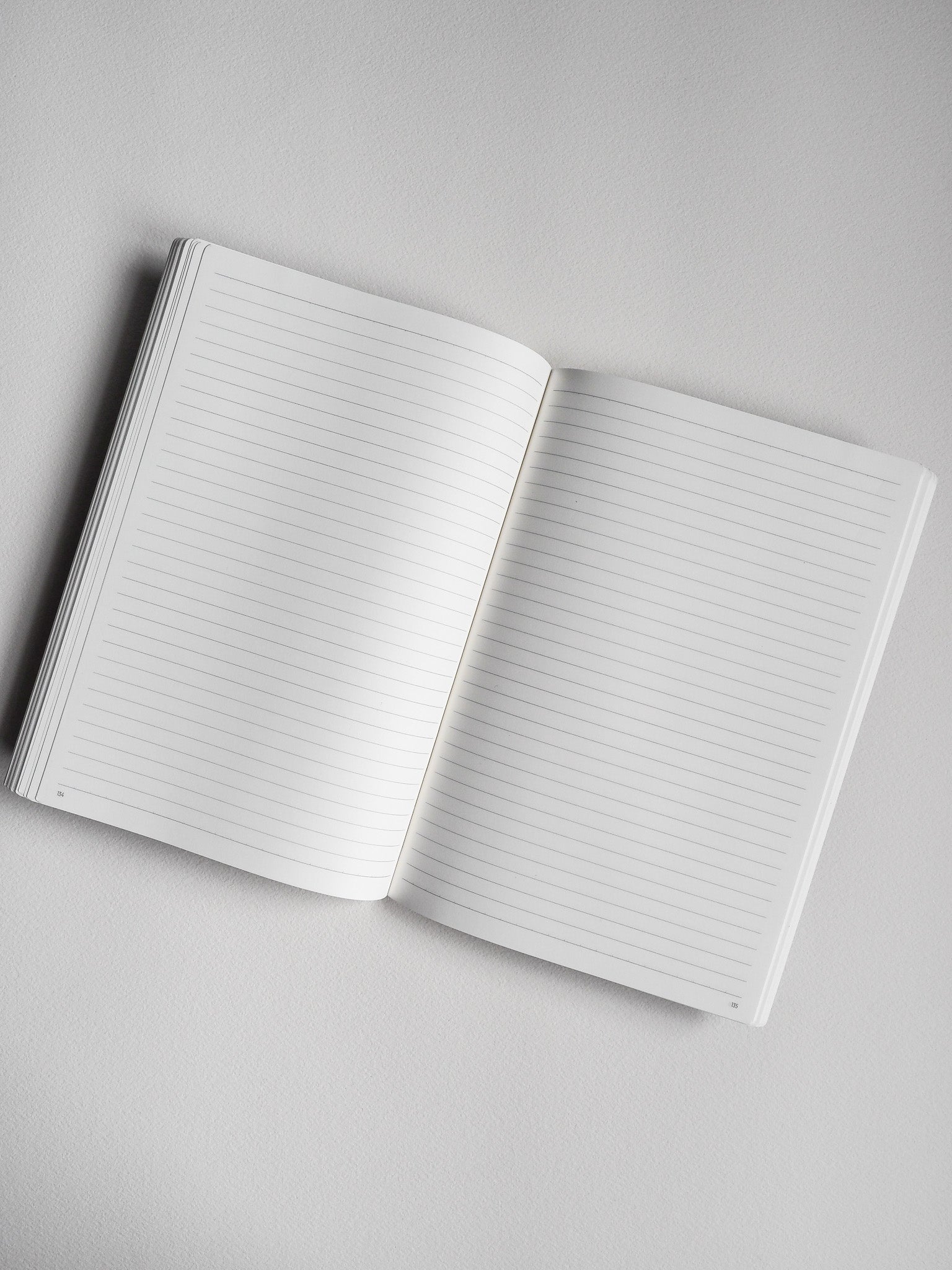 Open A5 ruled notebook showing two crisp white pages, designed for journaling and structured writing.