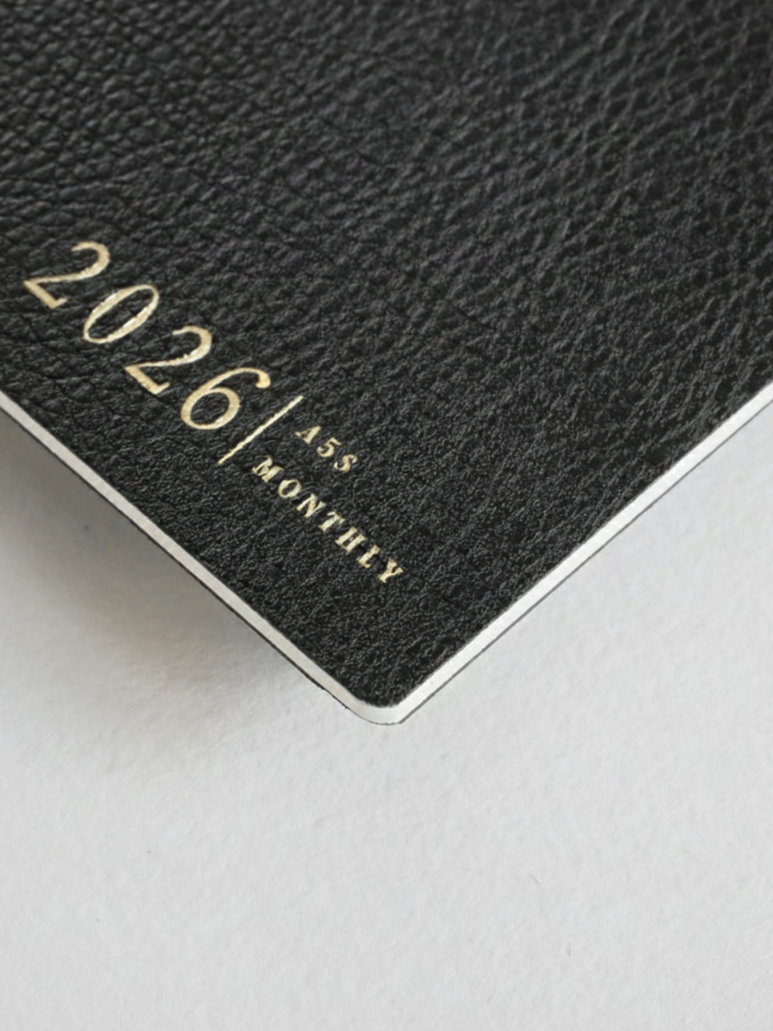 Sleek dark gray A5 monthly booklet cover featuring embossed gold lettering that clearly displays "2026 | A5 | MONTHLY."