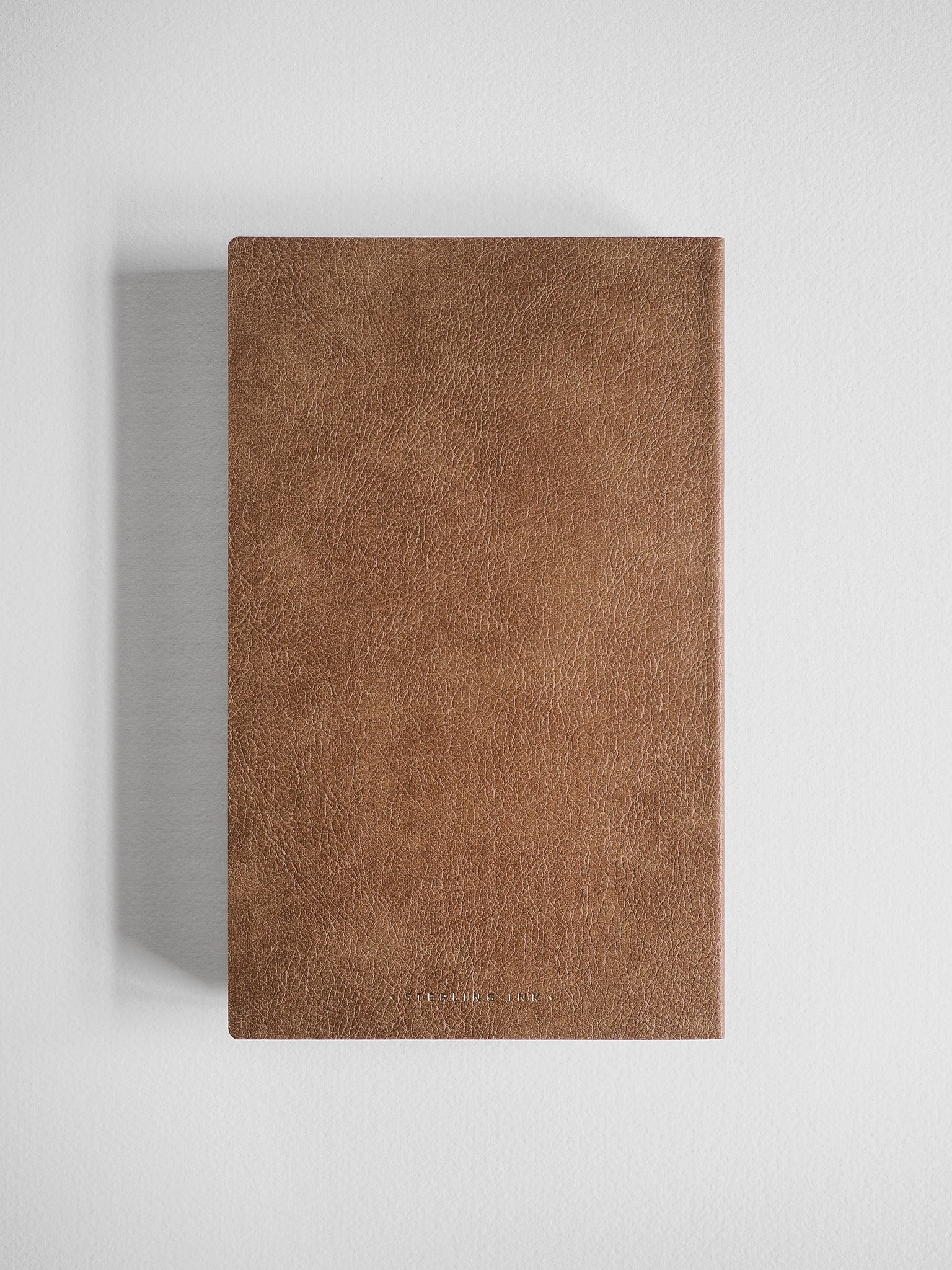 A slim A5 grid notebook featuring a richly textured, warm cocoa-brown faux-leather cover, perfect for extensive journaling and studies.
