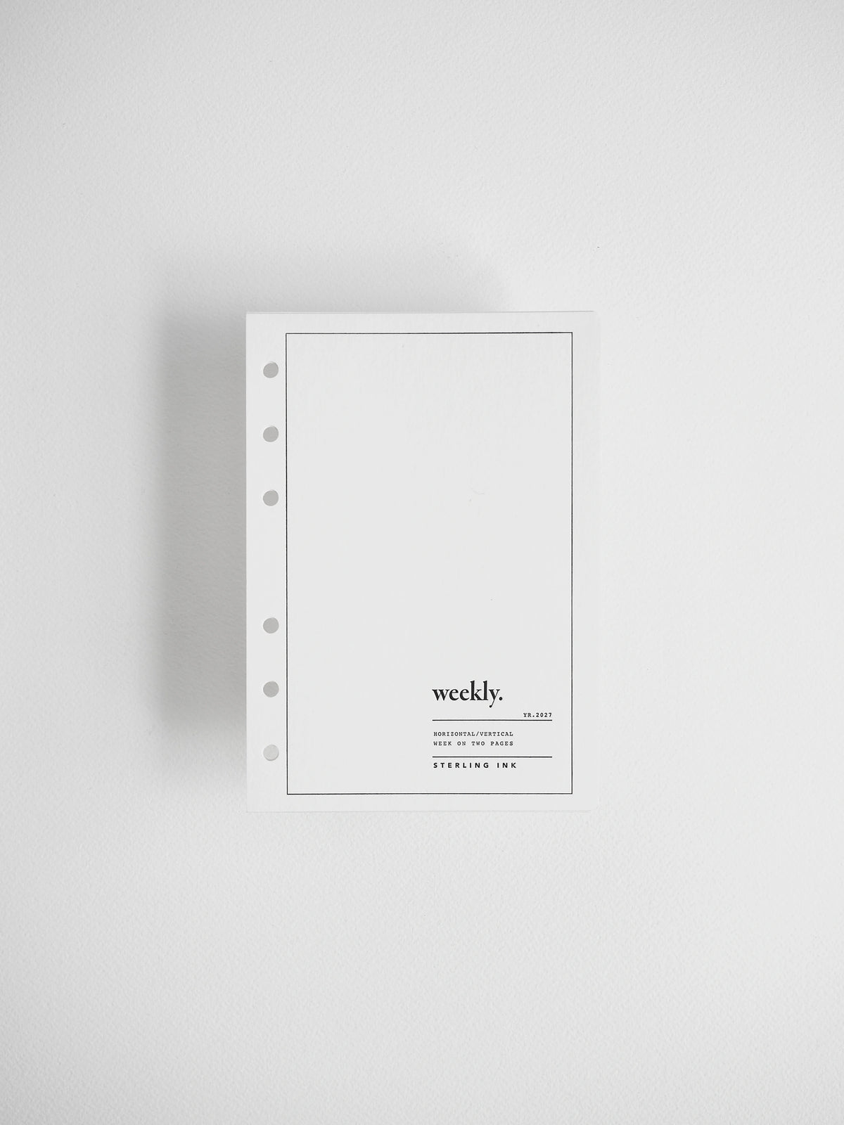 A minimalist white weekly planner insert with a five-hole punch on the left side, featuring the text 'weekly.' and 'STERLING INK' printed in black on the lower right, set against a clean white background.
#Size_A6