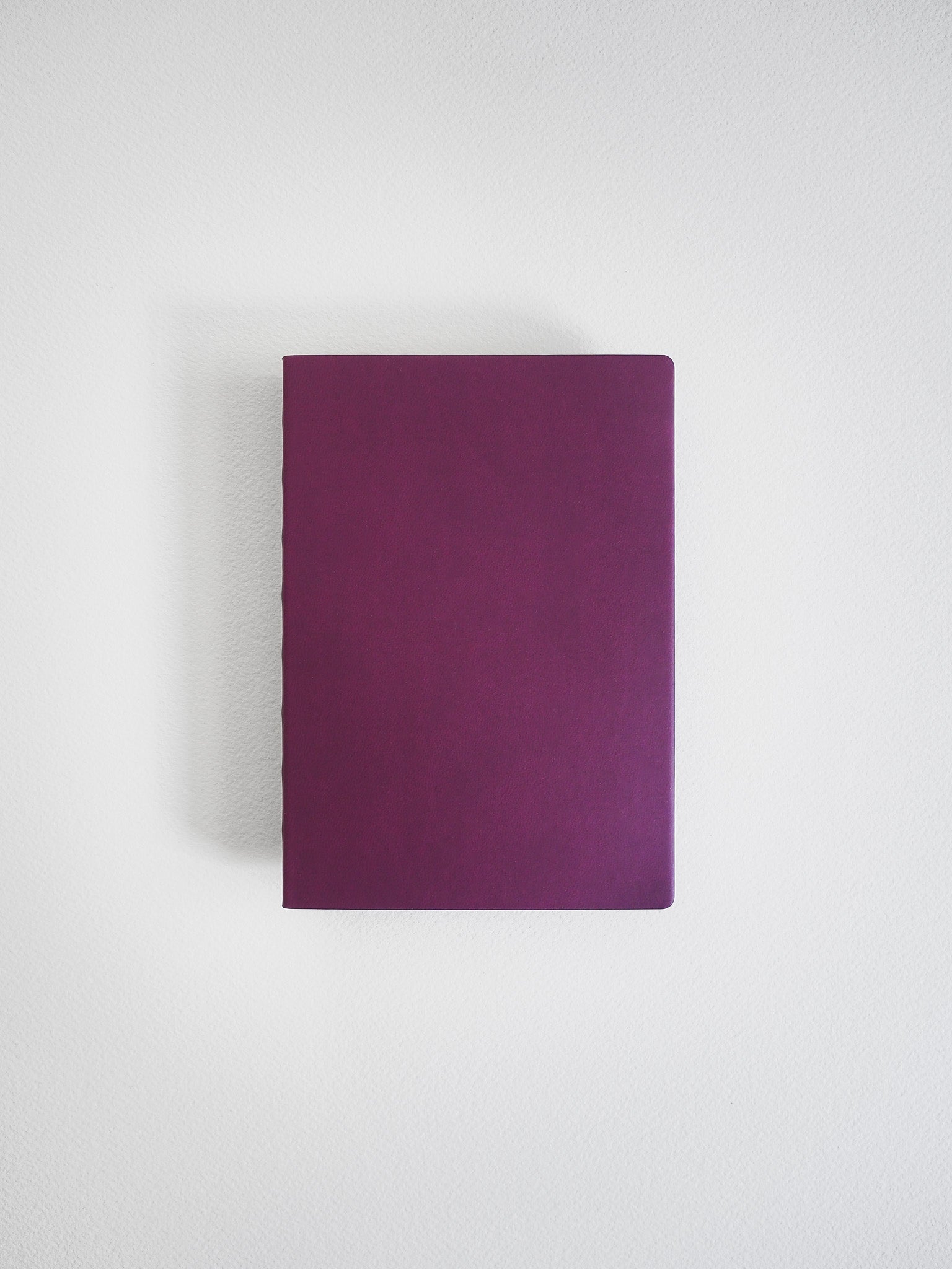 Solid deep mauve A6 notebook featuring a smooth, uniform cover, ideal for journaling, sketching, or detailed grid note-taking.