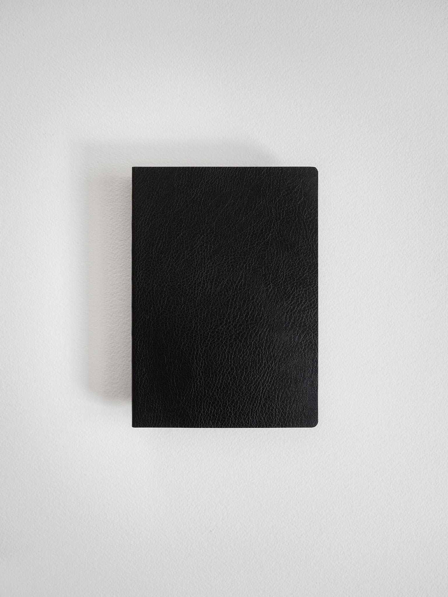 Sleek, A6-sized journal with a solid black, textured faux leather cover, ideal for grid-notebook layouts and writing notes.