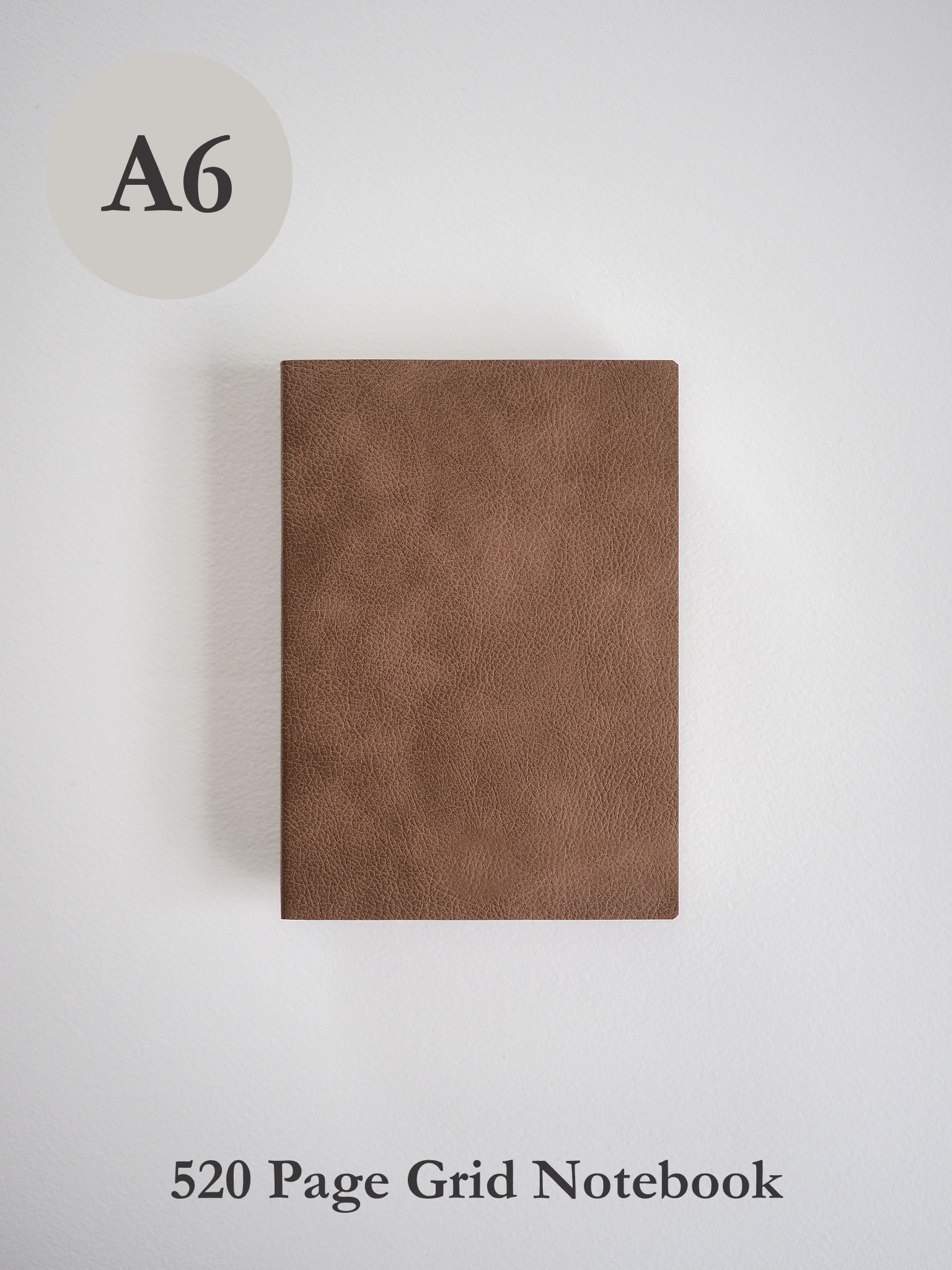 A plain, solid matte brown A6 grid notebook with a smooth, tactile faux leather cover.