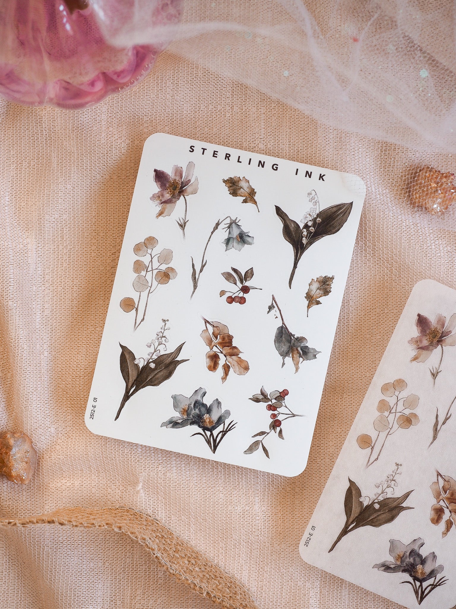 Elegant sticker sheet featuring muted botanical elements, including delicate dried foliage, small berries, and stylized flowers in sepia, dusty brown, and deep indigo tones.