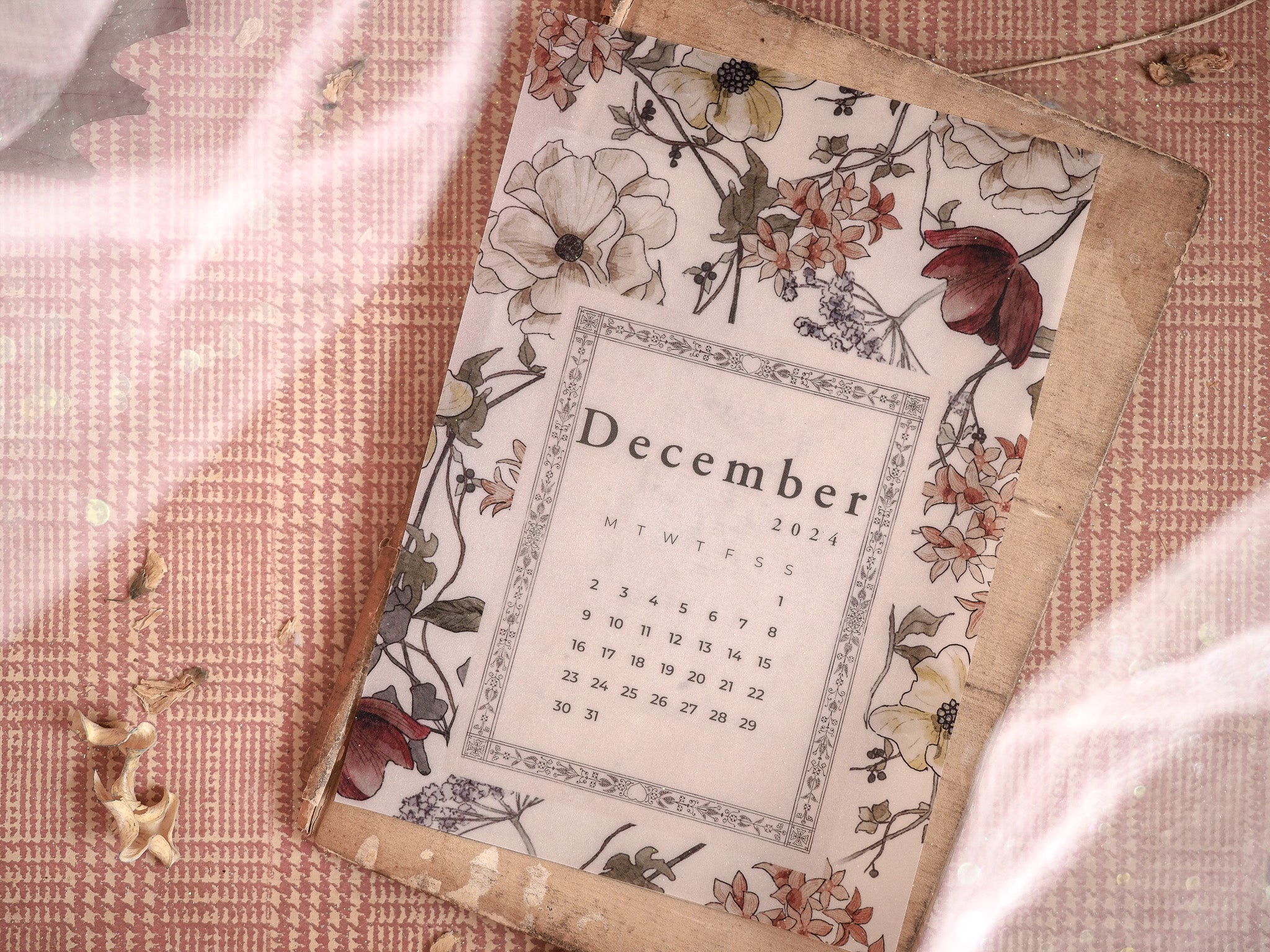 Elegant December 2024 monthly calendar featuring intricate vintage botanical illustrations of cream blossoms and rich red foliage.