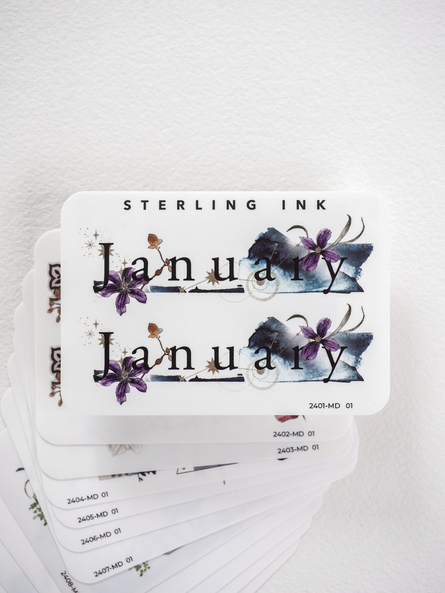 Printable planner stickers showing the word "January" elegantly decorated with rich purple and blue watercolor floral accents suitable for monthly journaling.