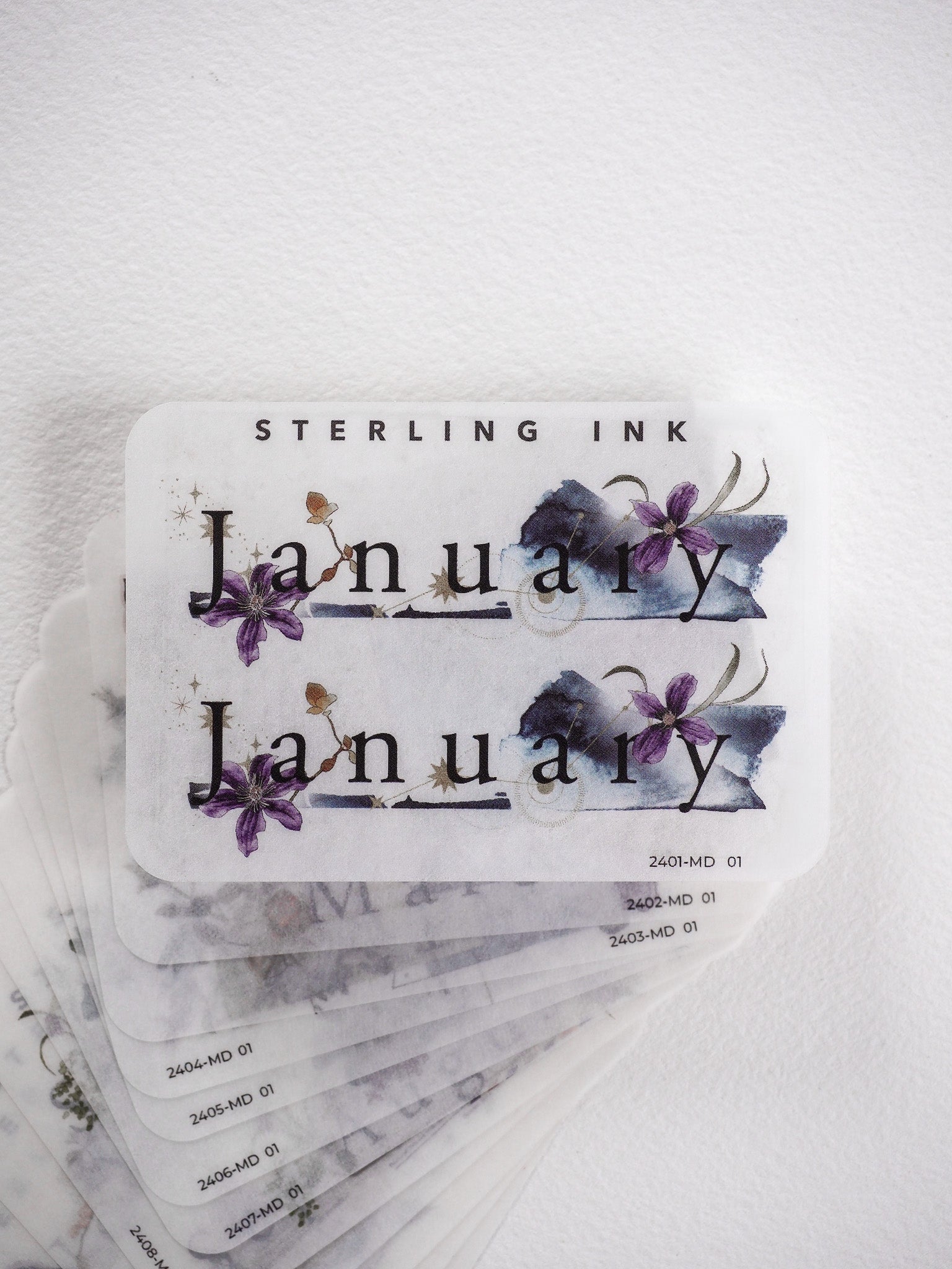 Watercolor monthly planner stickers featuring the word "January" and elegant purple floral accents, perfect for journaling or scrapbooking.