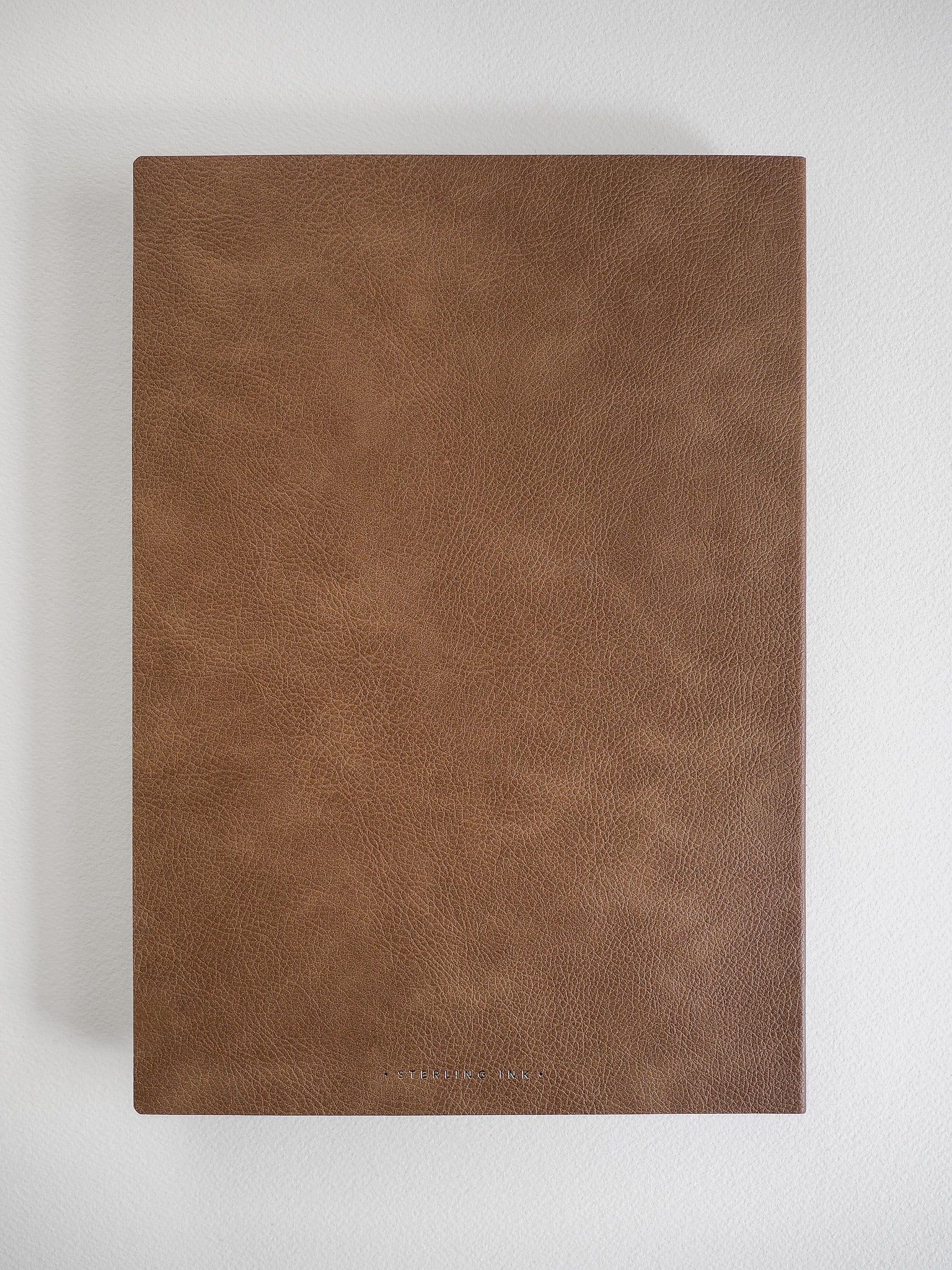 Minimalist B5 grid notebook bound in solid, textured earthy brown material, ideal for journaling and studying.