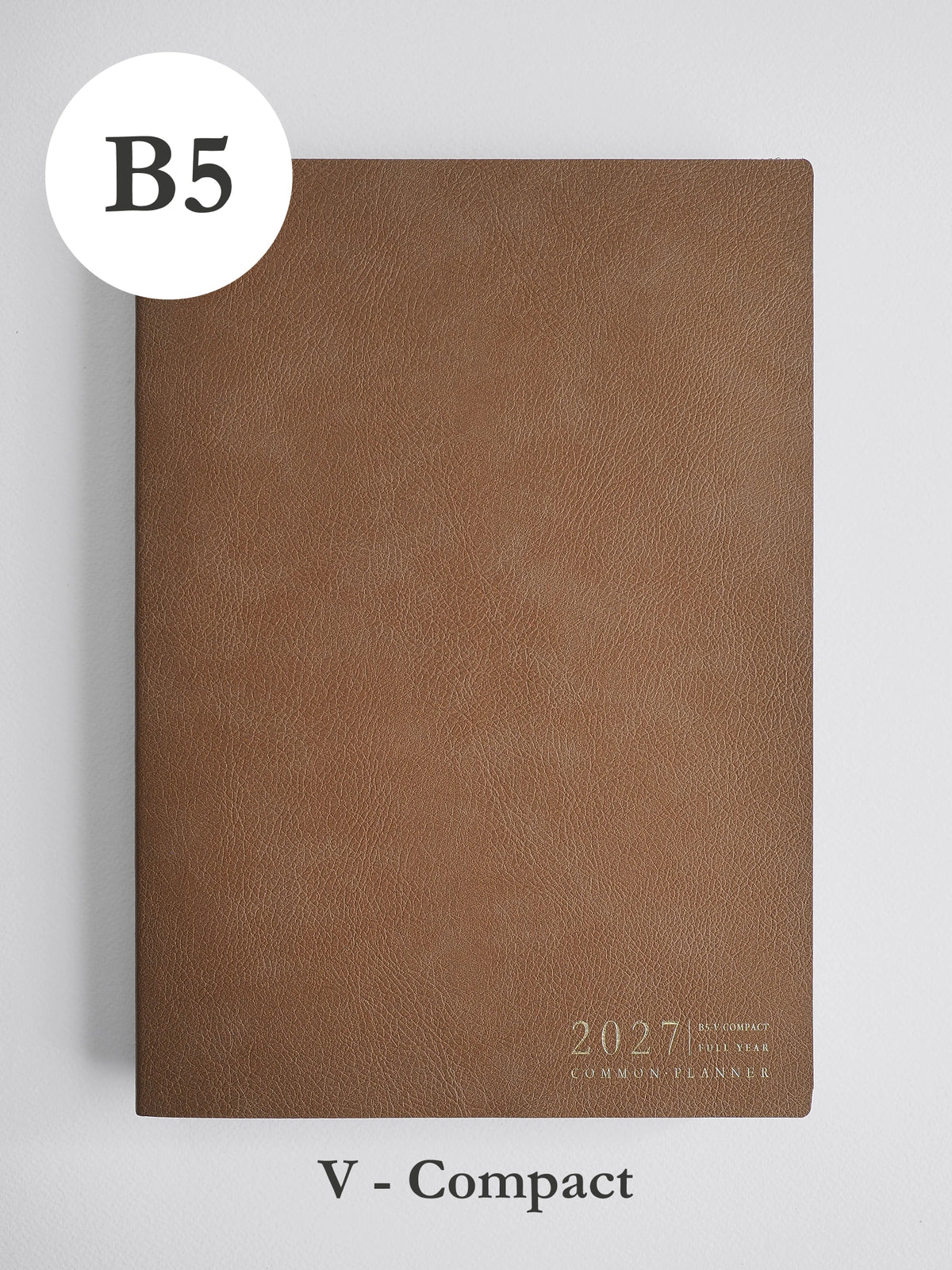 A brown textured 2027 compact planner shown closed on a light gray background, with a white circular label reading B5 at top left and the text 'V - Compact' below.
#Color_Caramel